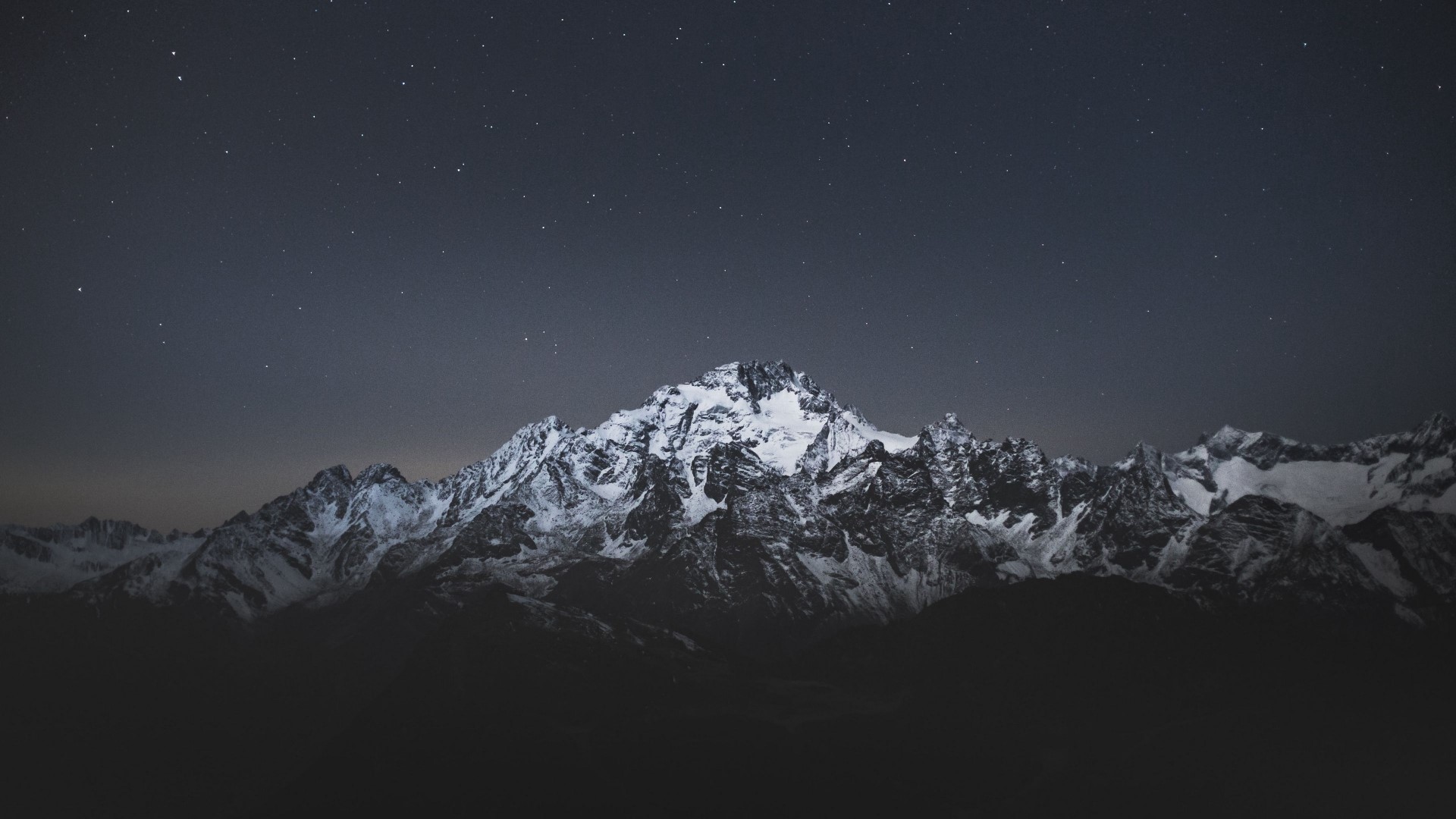 Snow-covered mountains under a starry night sky HD Wallpaper