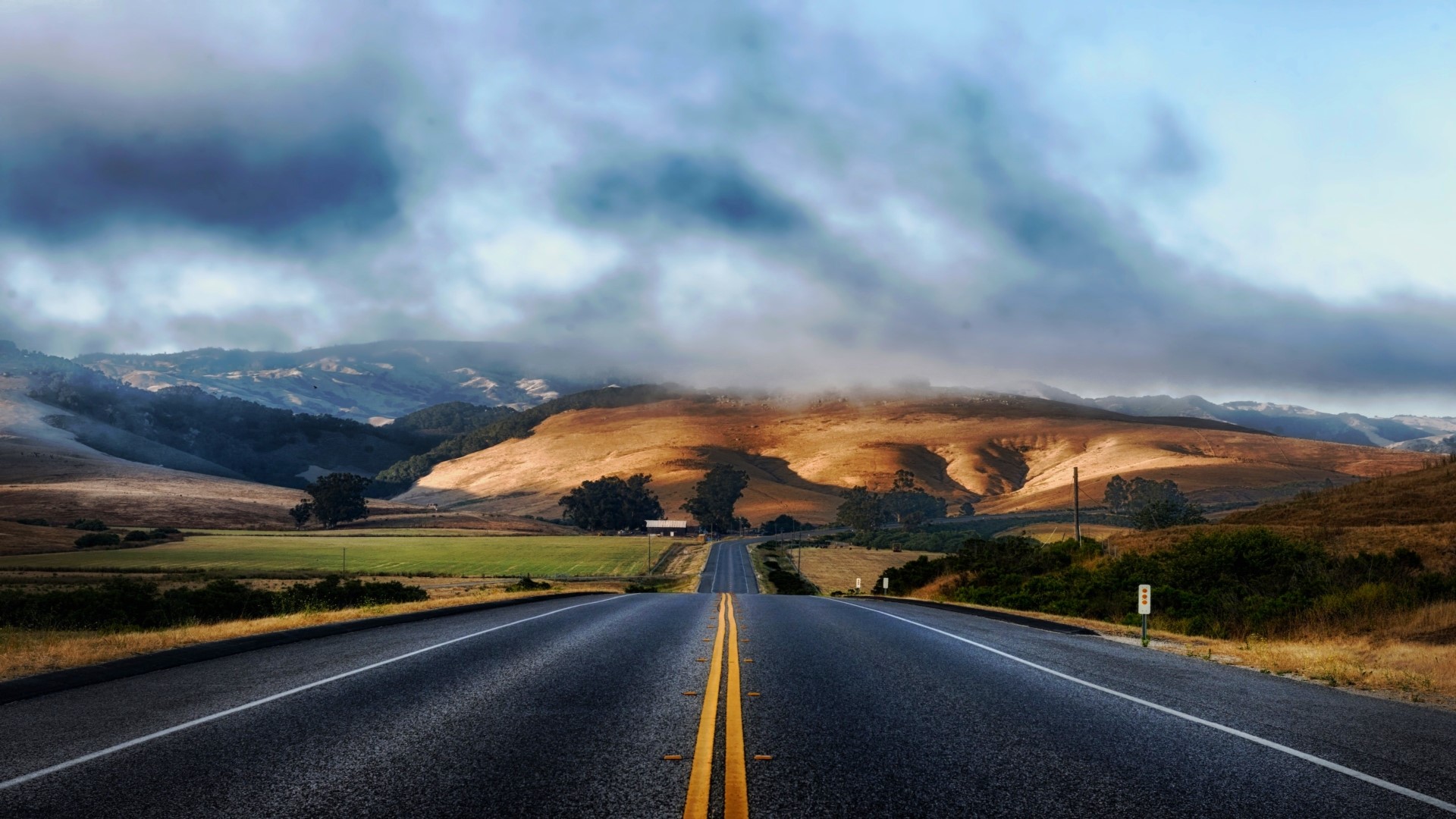 Road leading to rolling hills under cloudy sky HD Wallpaper