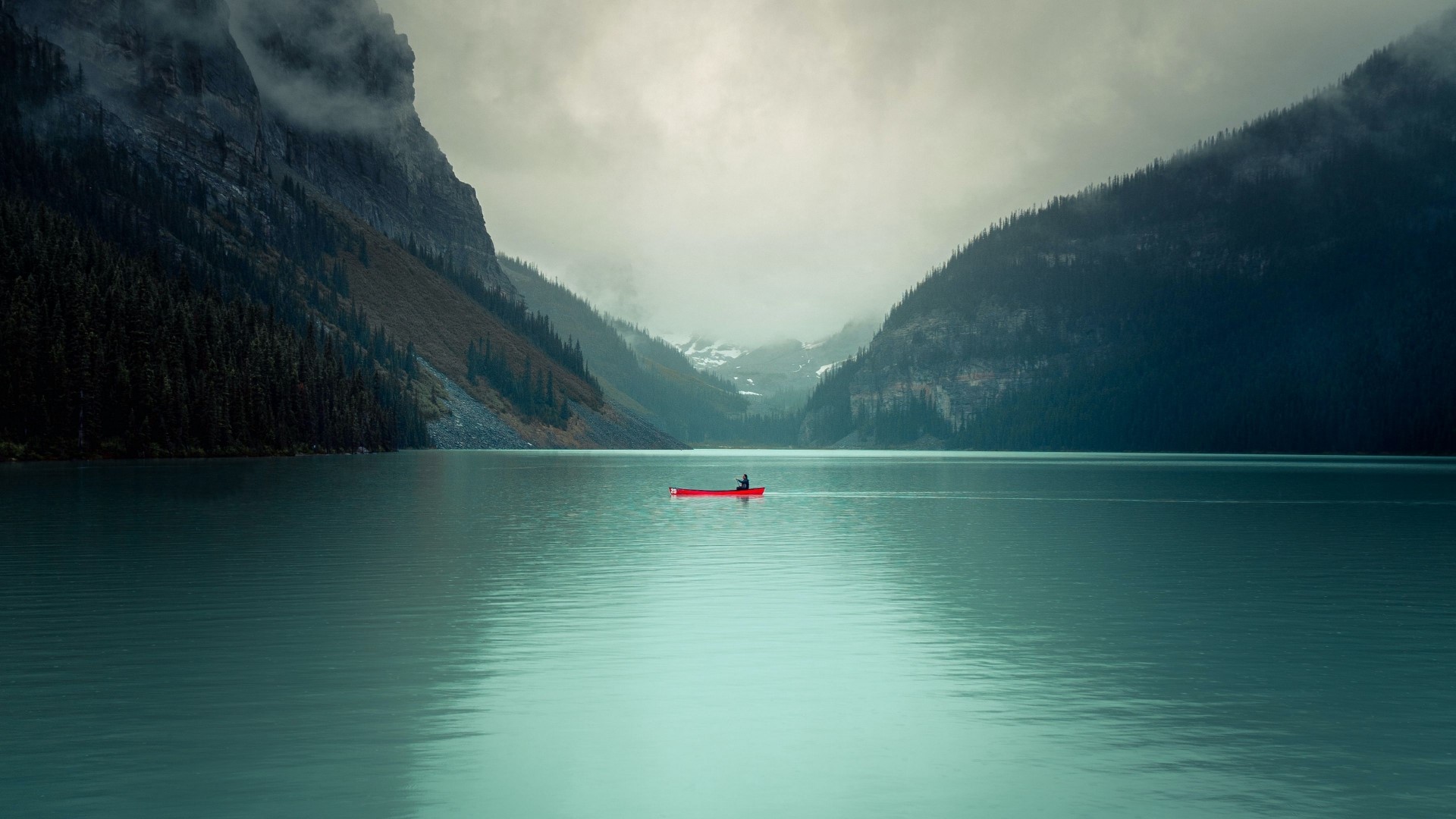 Person in a red canoe on a lake with mountains HD Wallpaper
