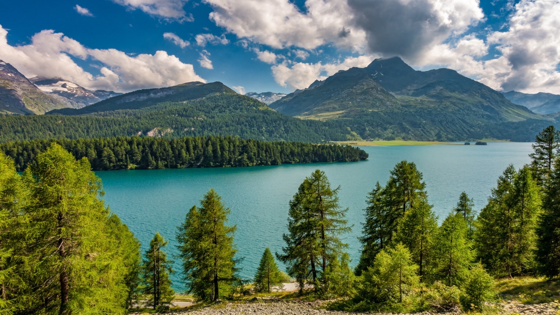 Turquoise lake surrounded by pine forest and mountains HD Wallpaper