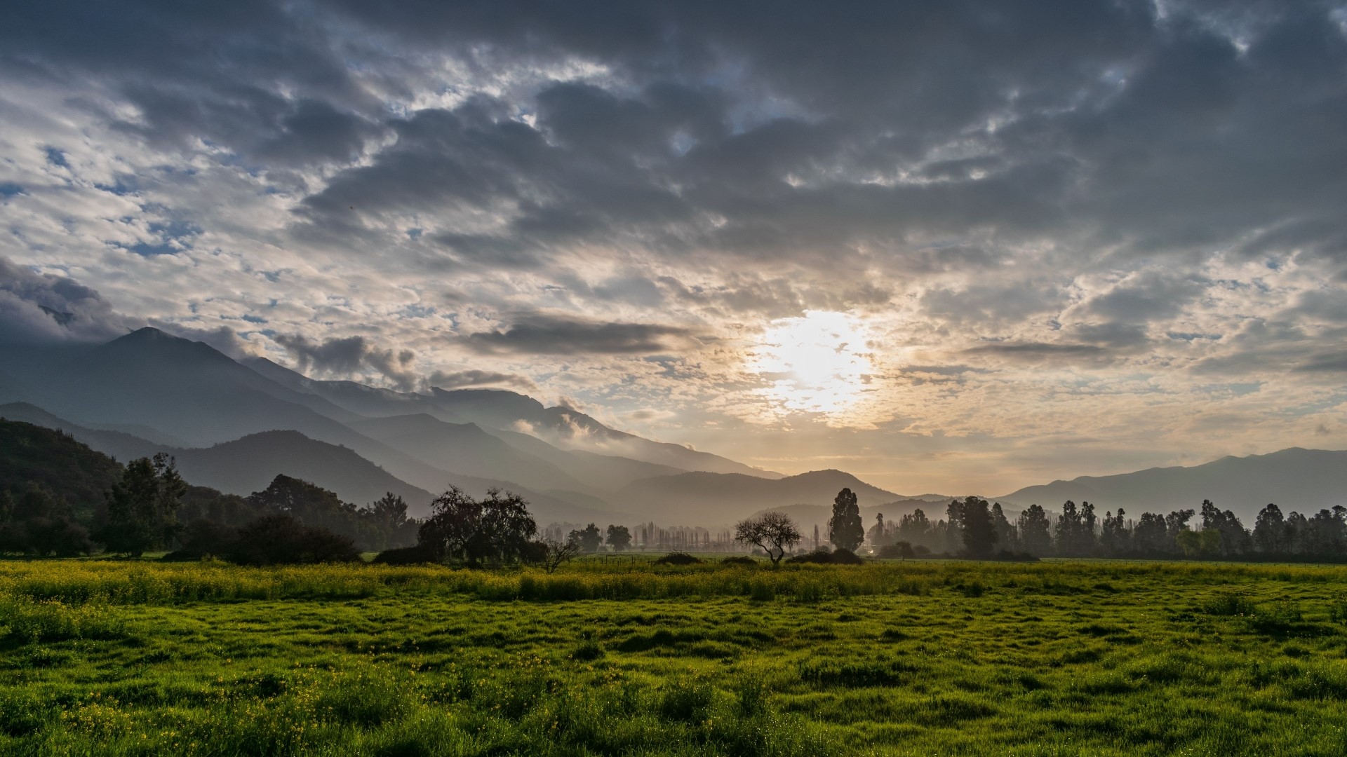 Sunlight over misty mountains and green field HD Wallpaper