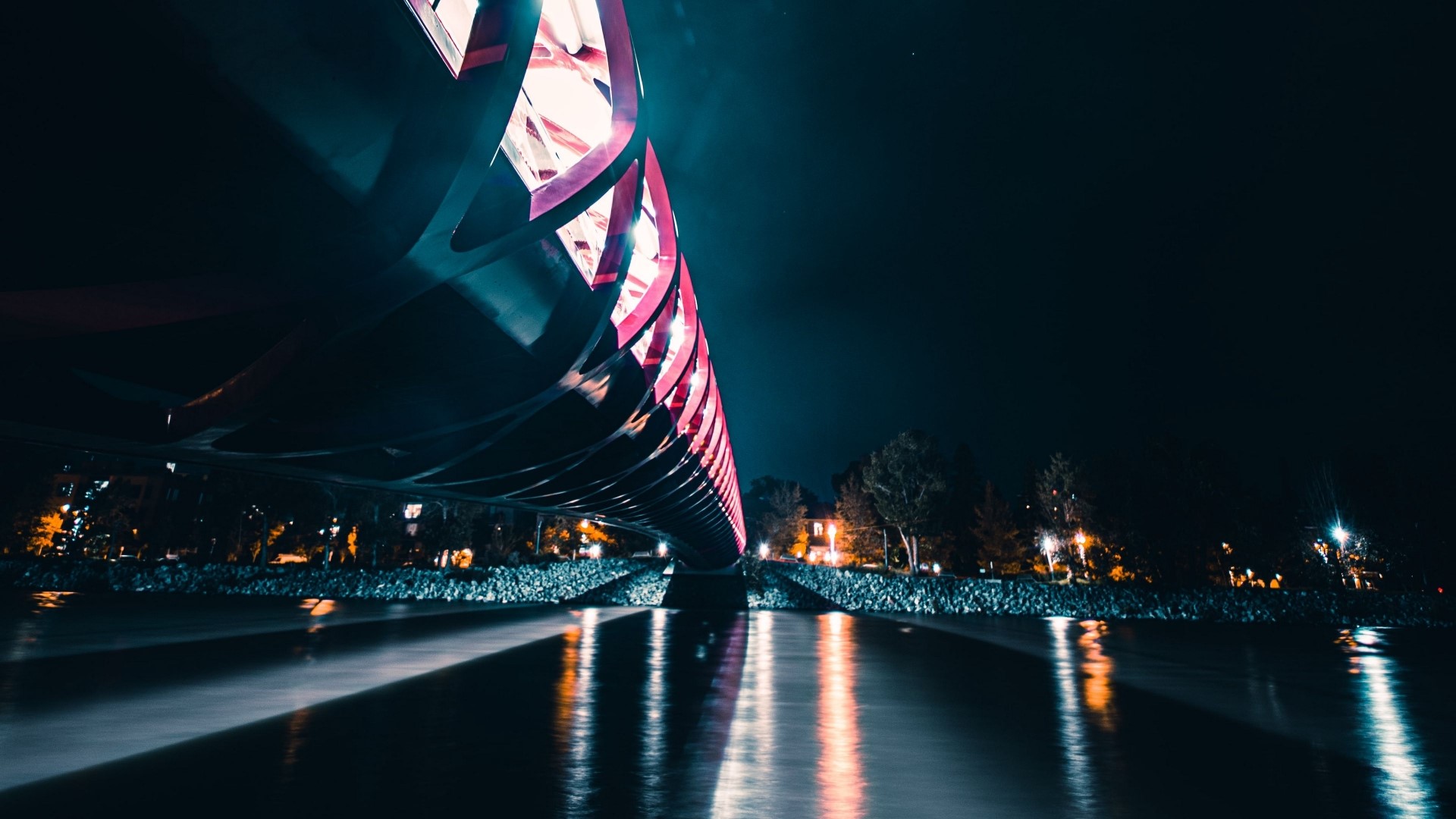 Bridge illuminated with pink lights over water at night HD Wallpaper