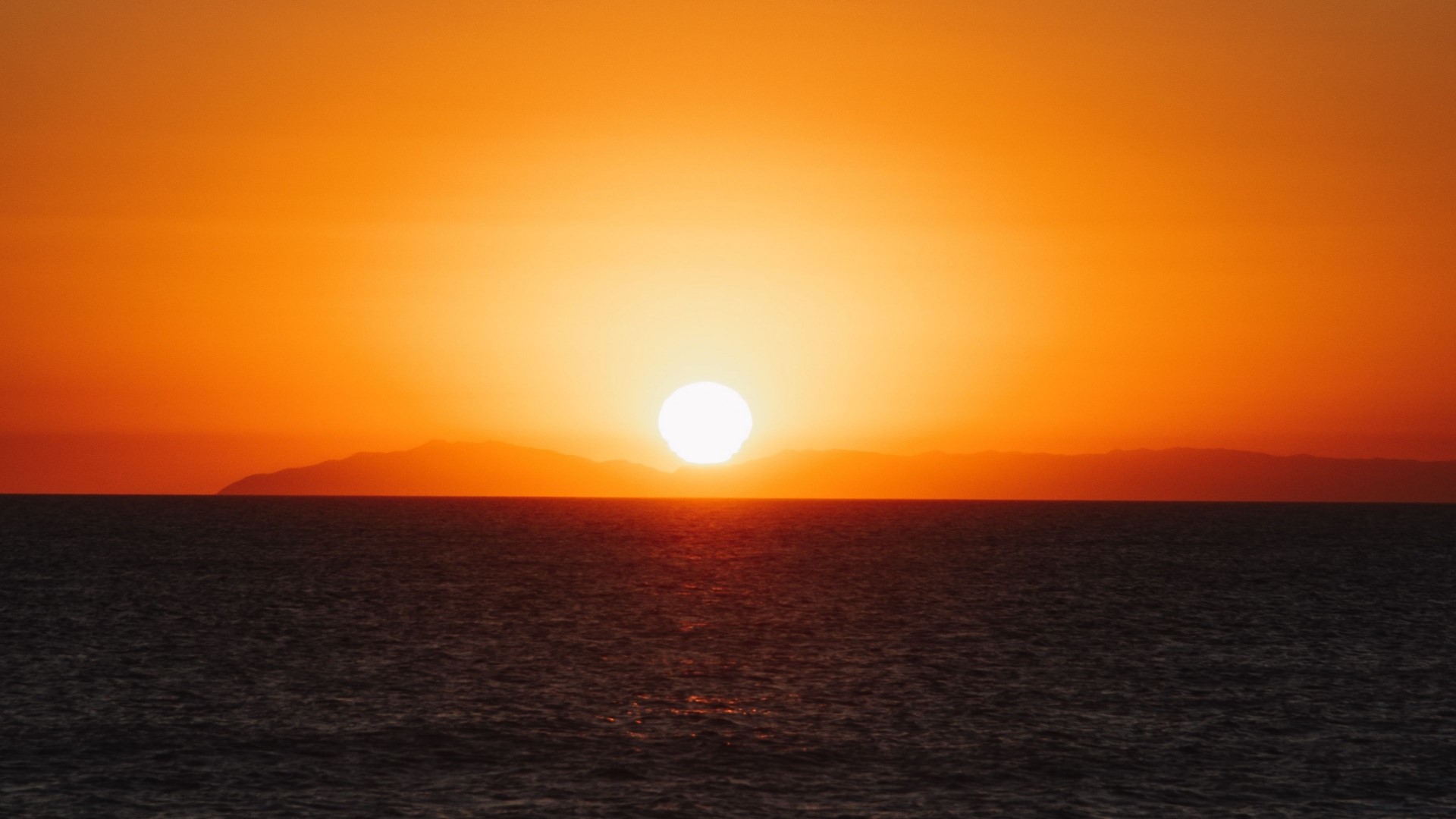 Sunset over the ocean with distant islands HD Wallpaper