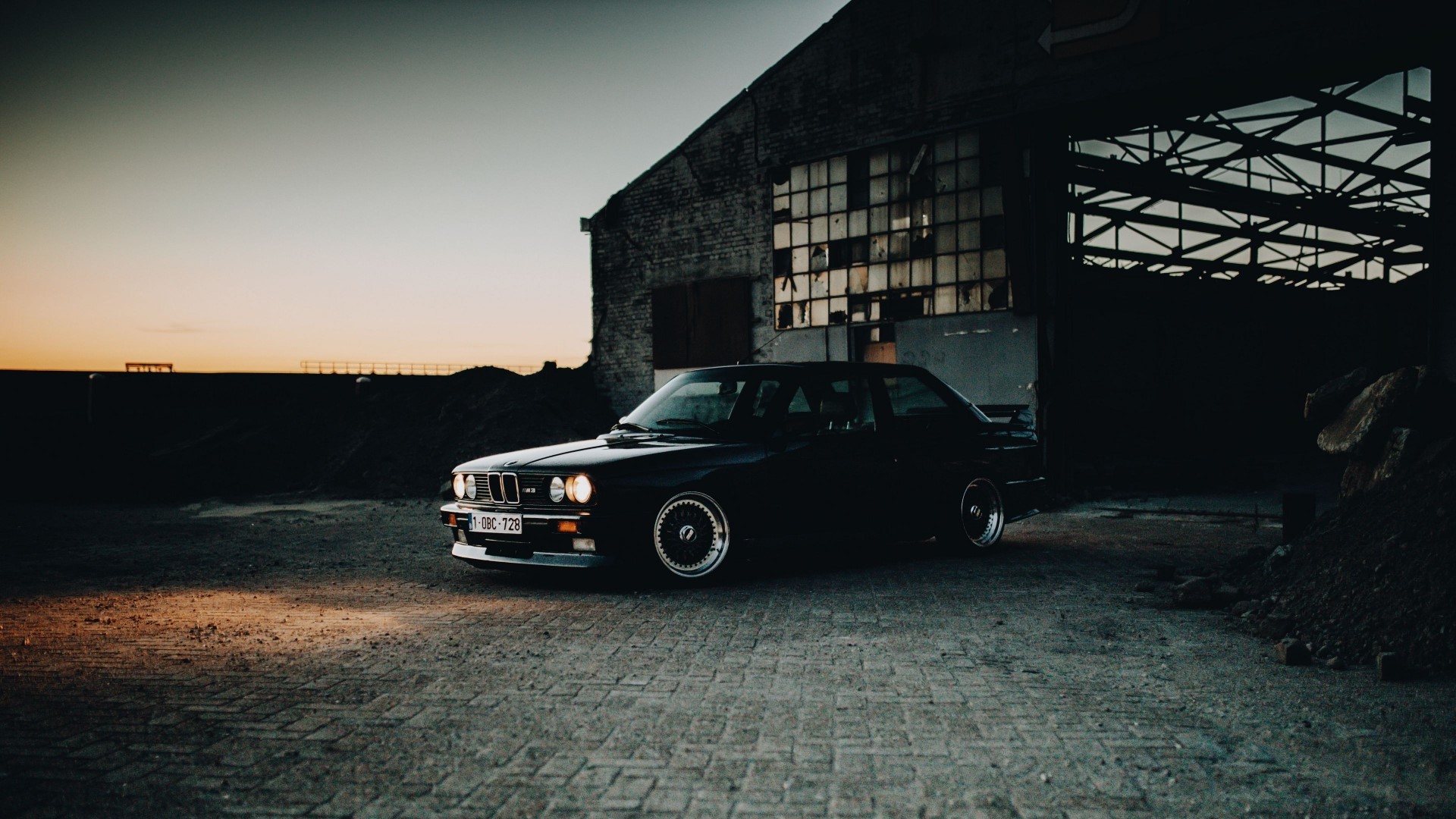 Black BMW E30 parked in front of an abandoned building HD Wallpaper