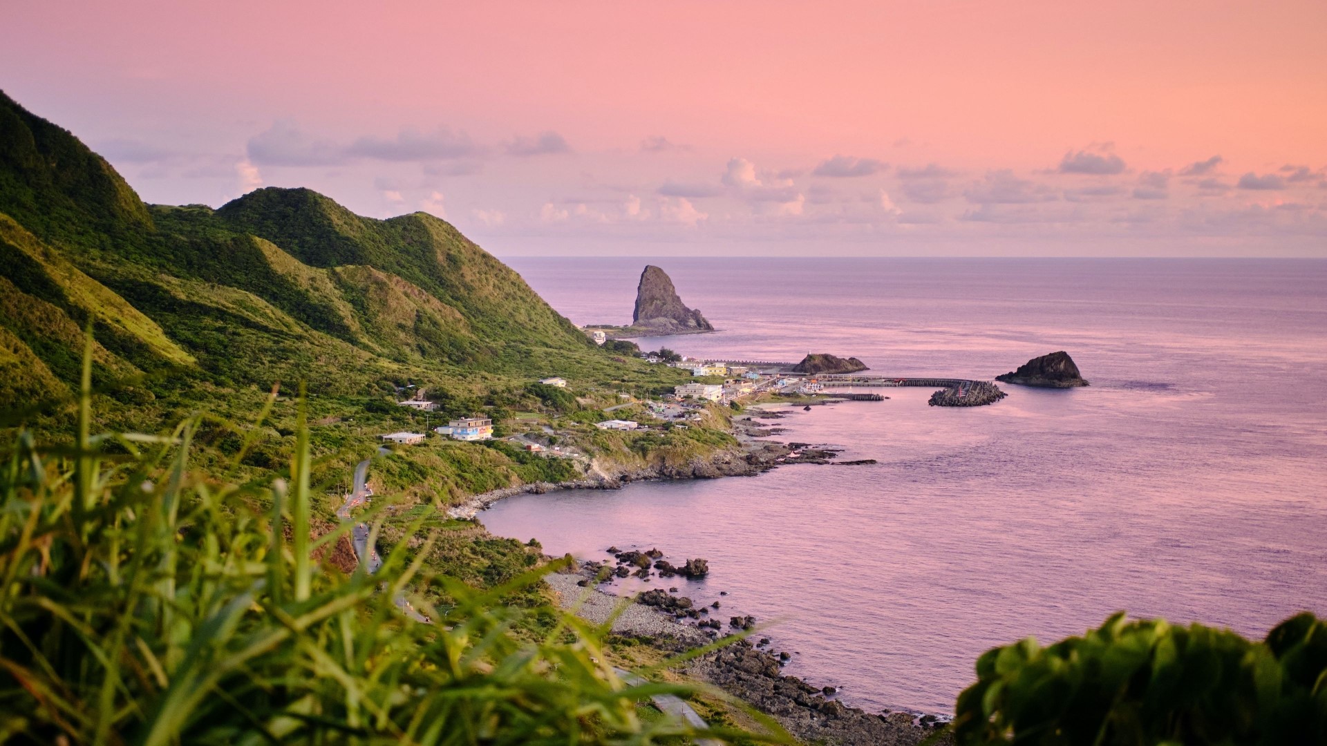 Coastal village with green hills and ocean at sunset HD Wallpaper