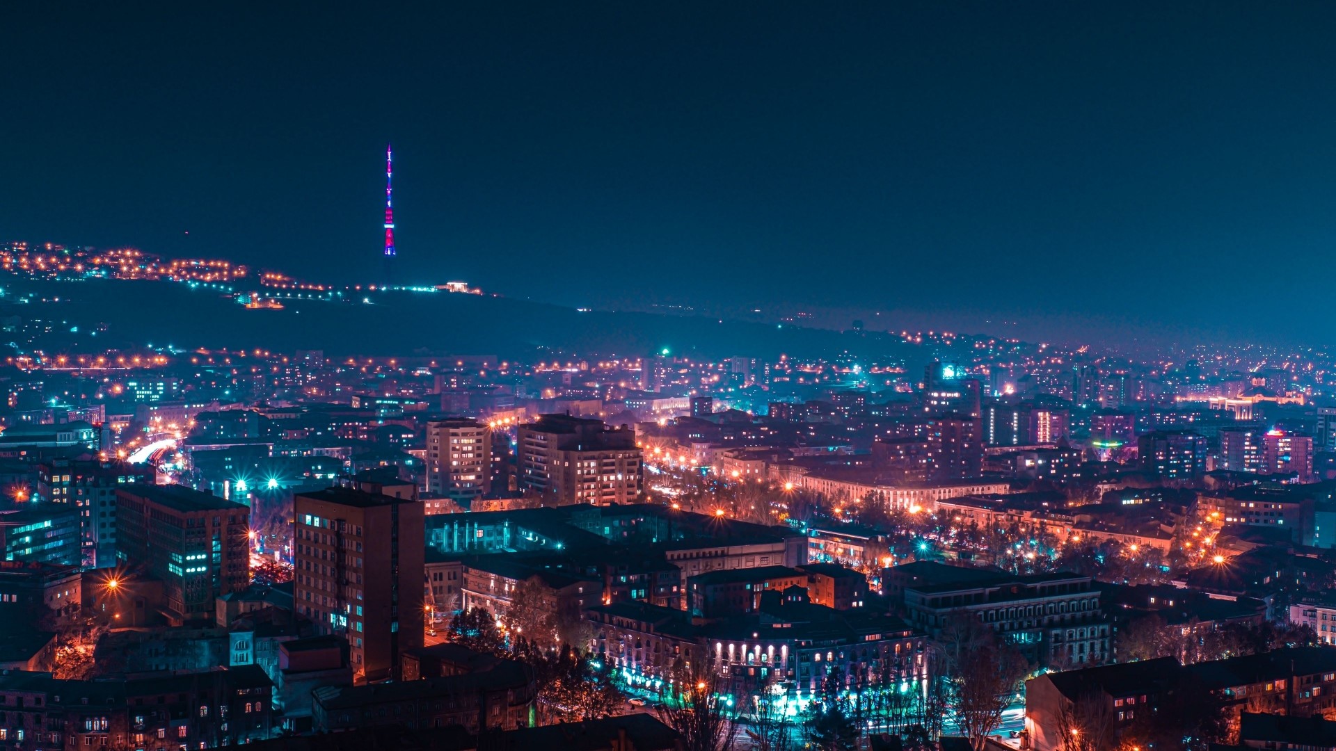 Night cityscape with illuminated buildings and a distant tower HD Wallpaper