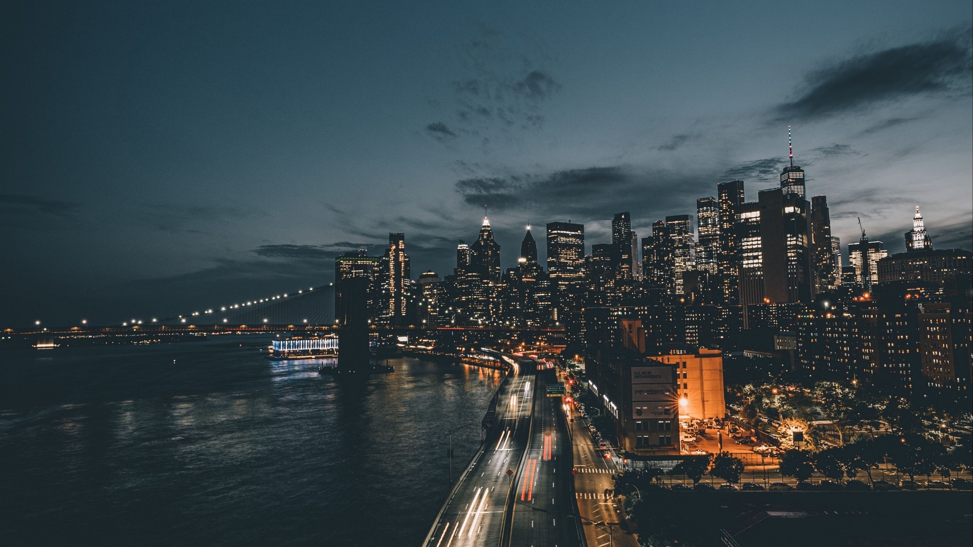 Nighttime cityscape with illuminated skyscrapers and bridge HD Wallpaper