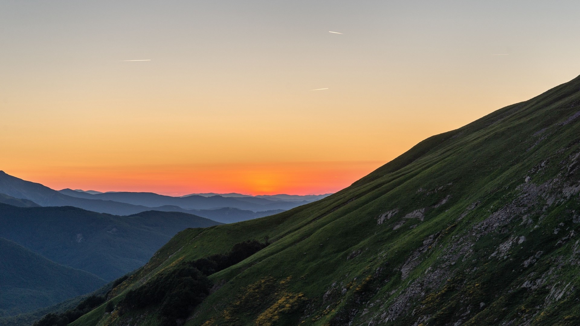 Sunset over mountain ranges with green hills HD Wallpaper
