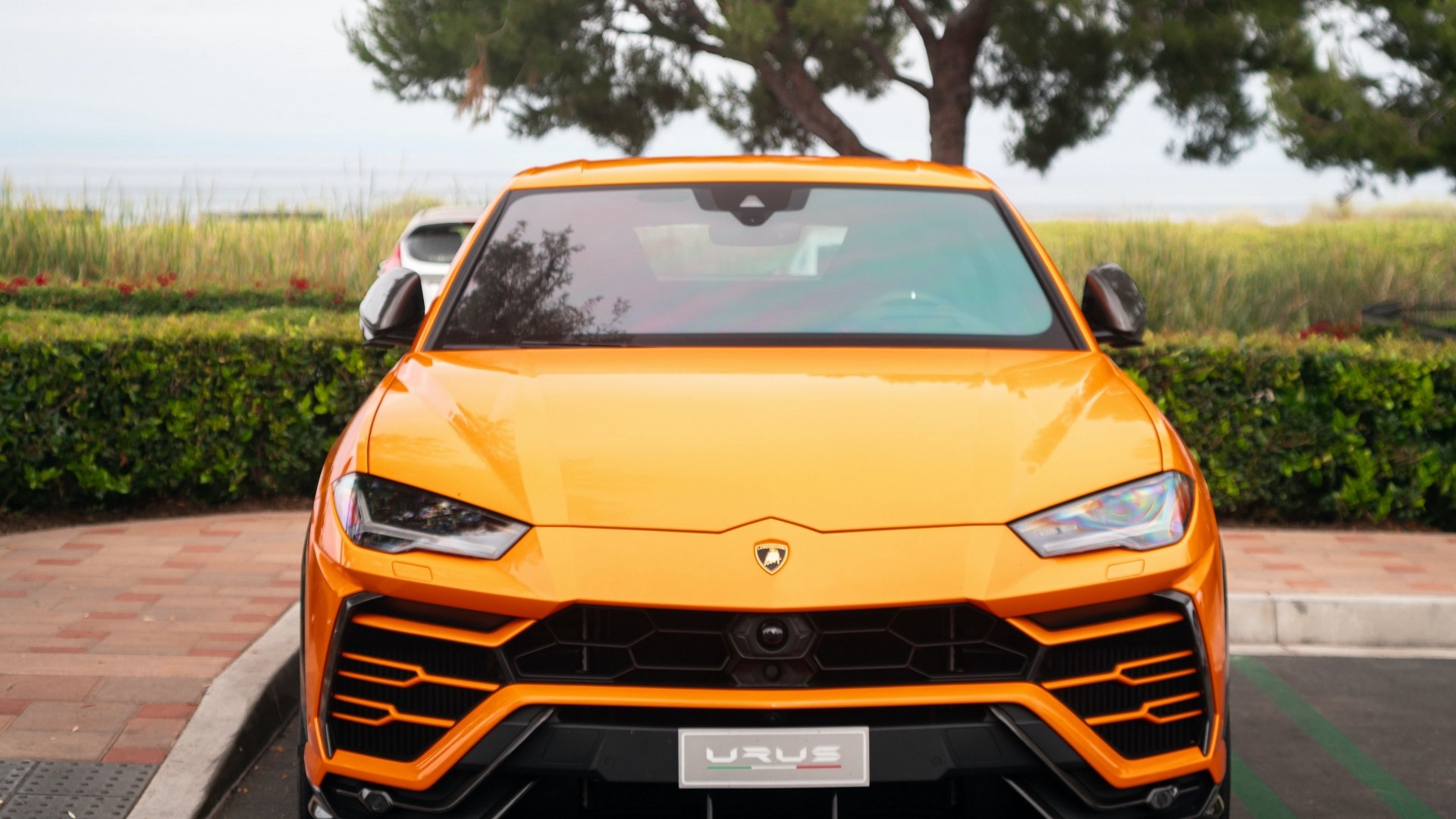 Orange Lamborghini Urus parked outdoors HD Wallpaper