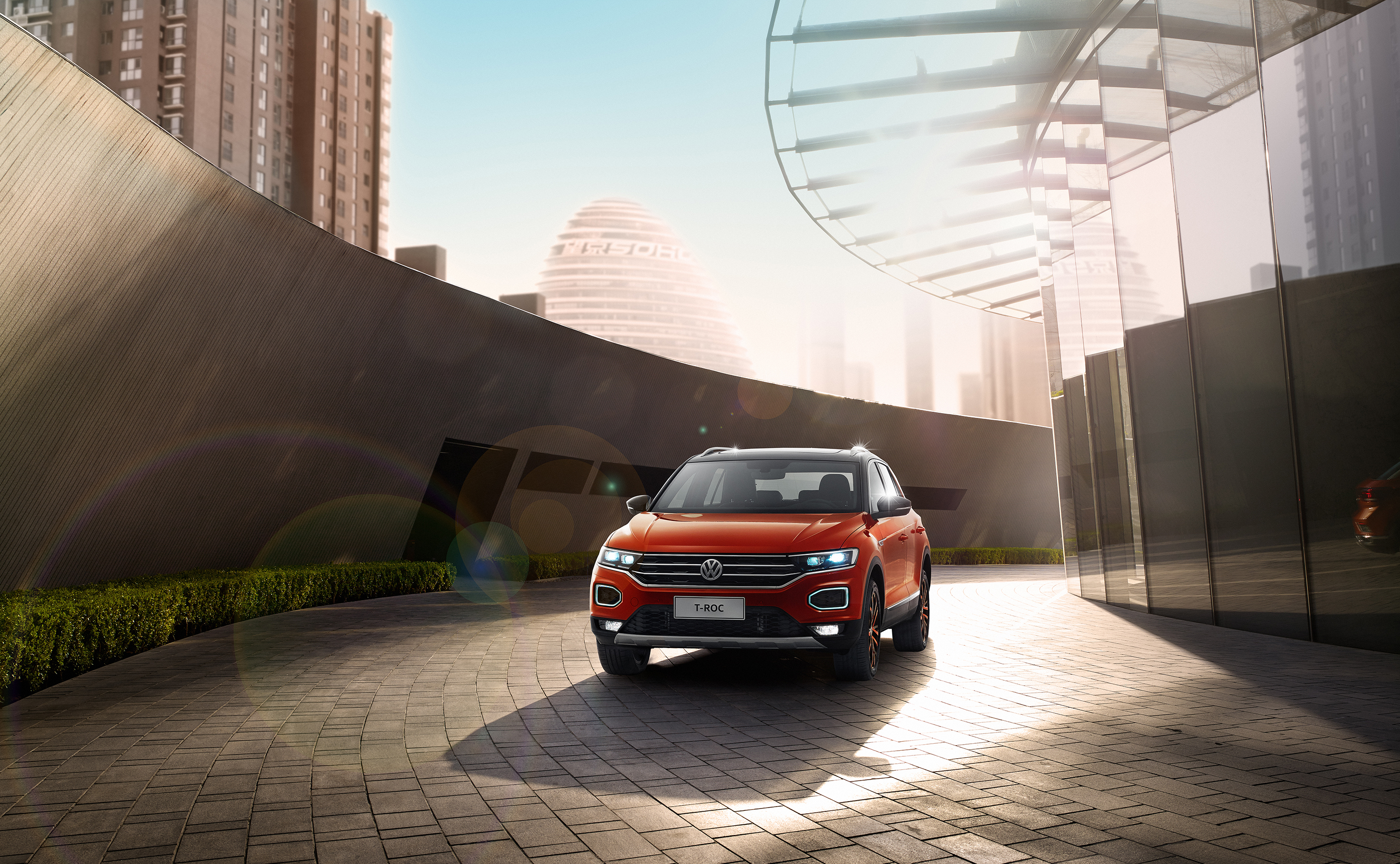 Orange Volkswagen T-Roc 4MOTION parked outside modern buildings HD Wallpaper