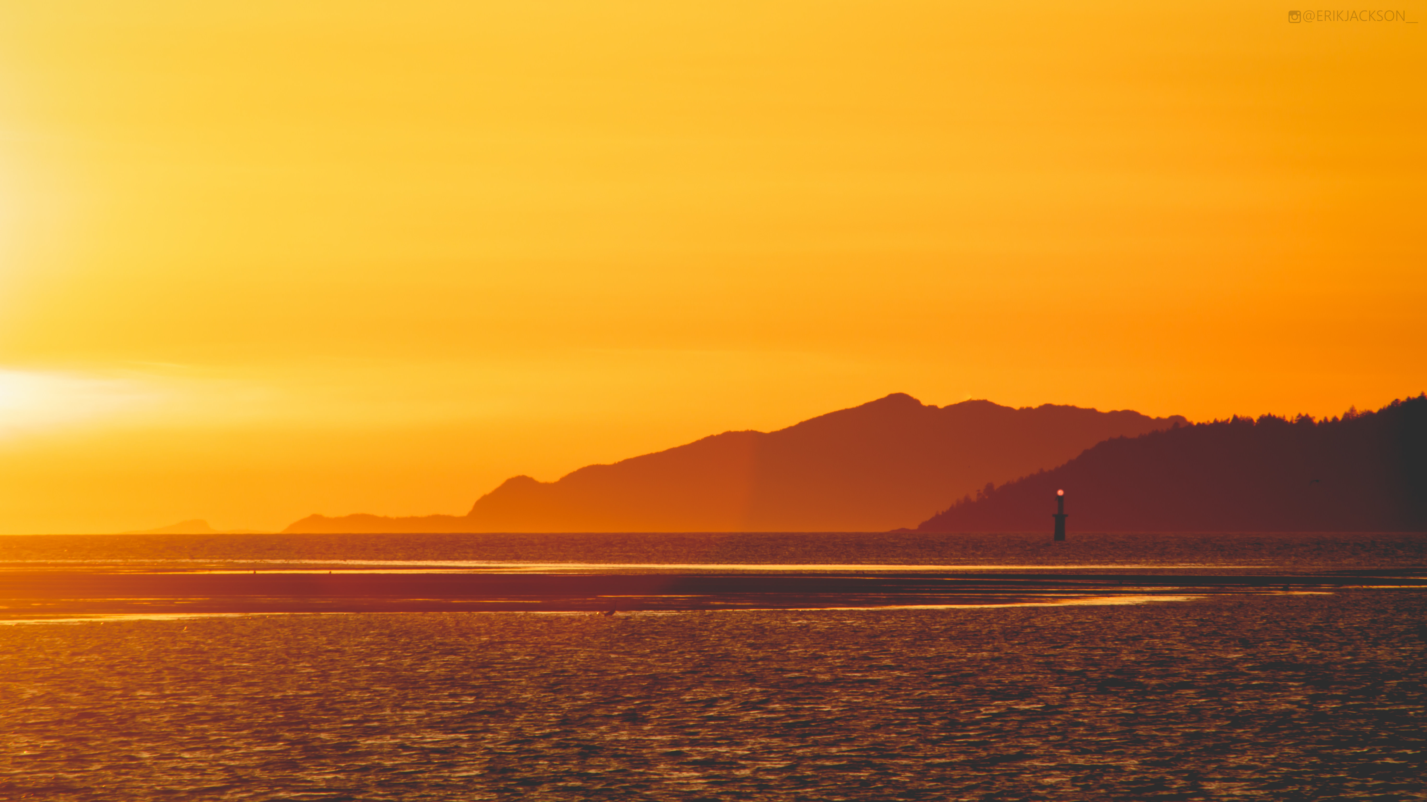 Sunset over the ocean with mountains and lighthouse HD Wallpaper