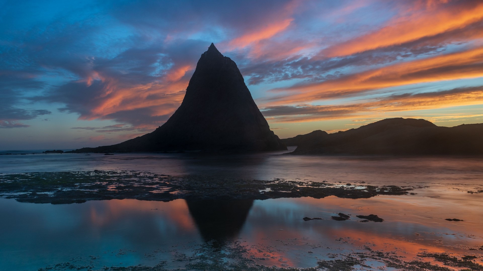 Silhouette of a pointed rock formation at sunset HD Wallpaper