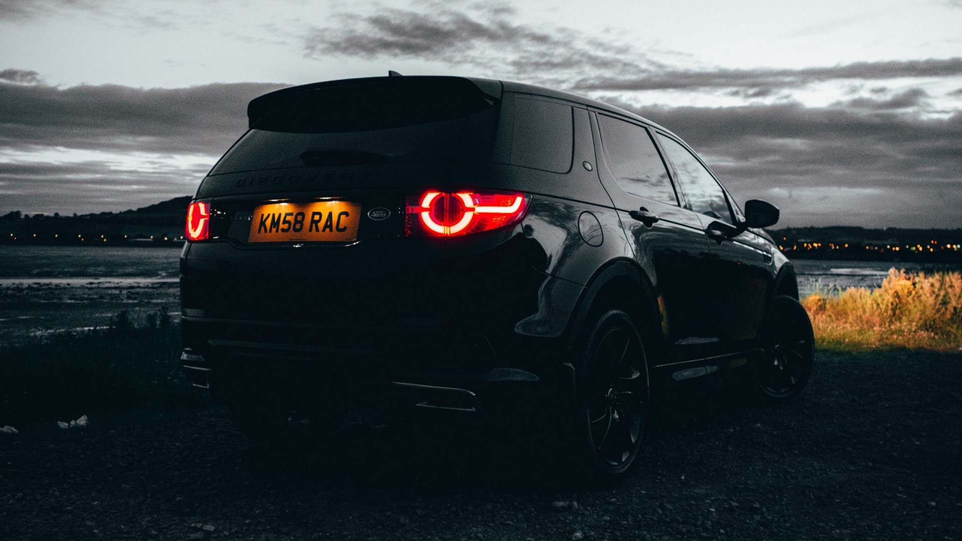 Black Land Rover Discovery Sport parked by a lake at dusk HD Wallpaper