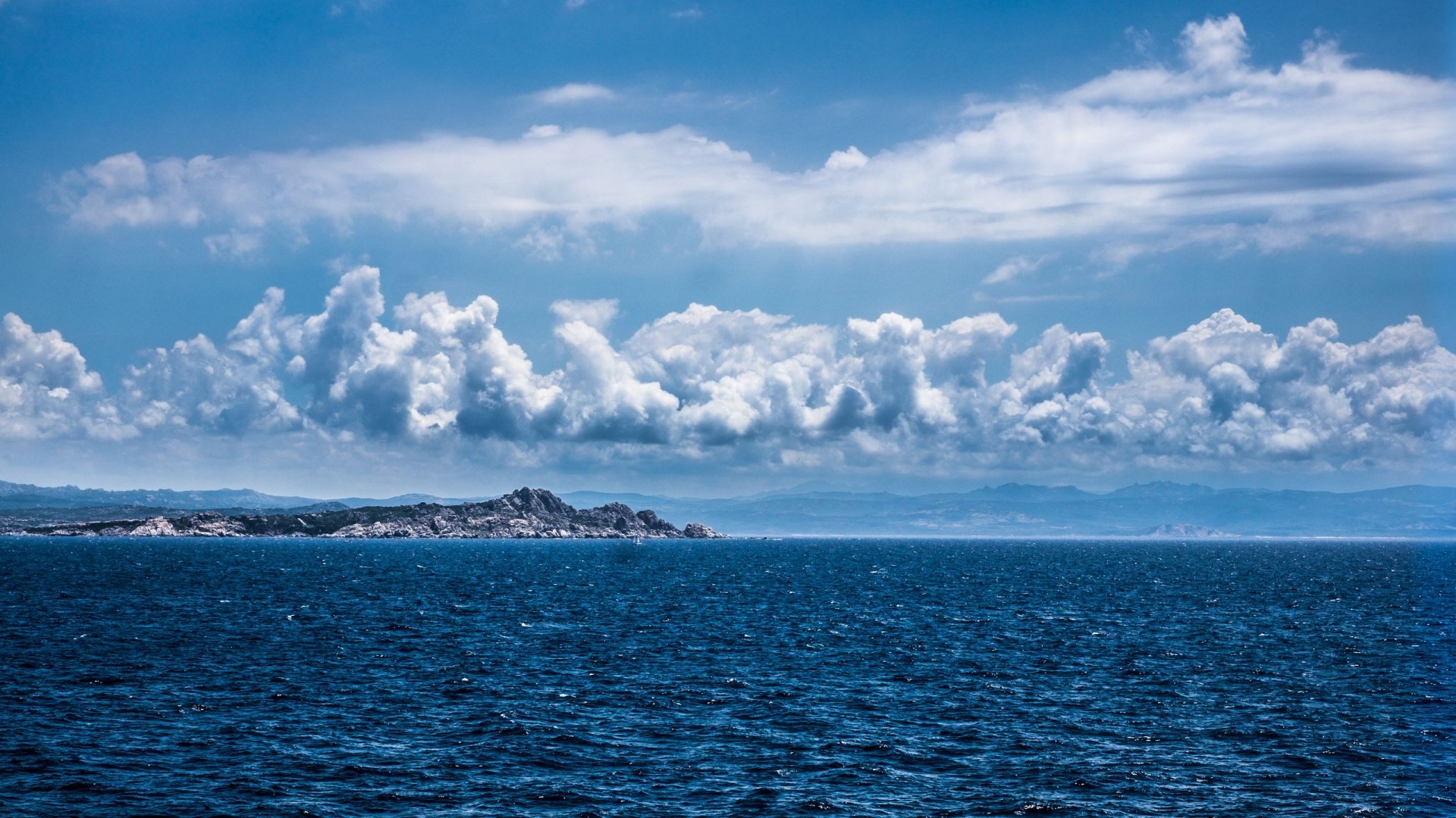 Rocky island in the sea under cloudy sky HD Wallpaper