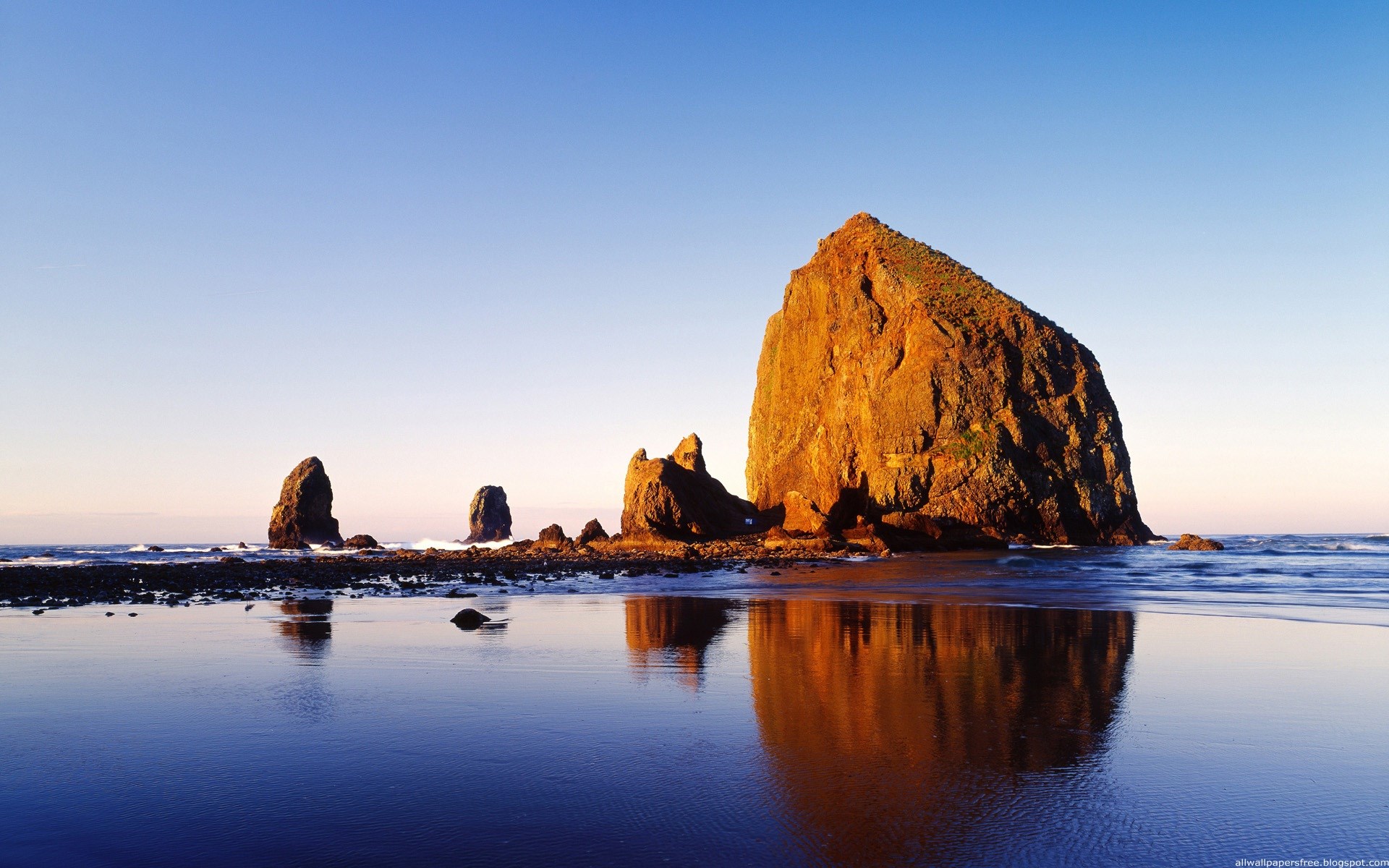 Large rock formation on a beach at sunset HD Wallpaper