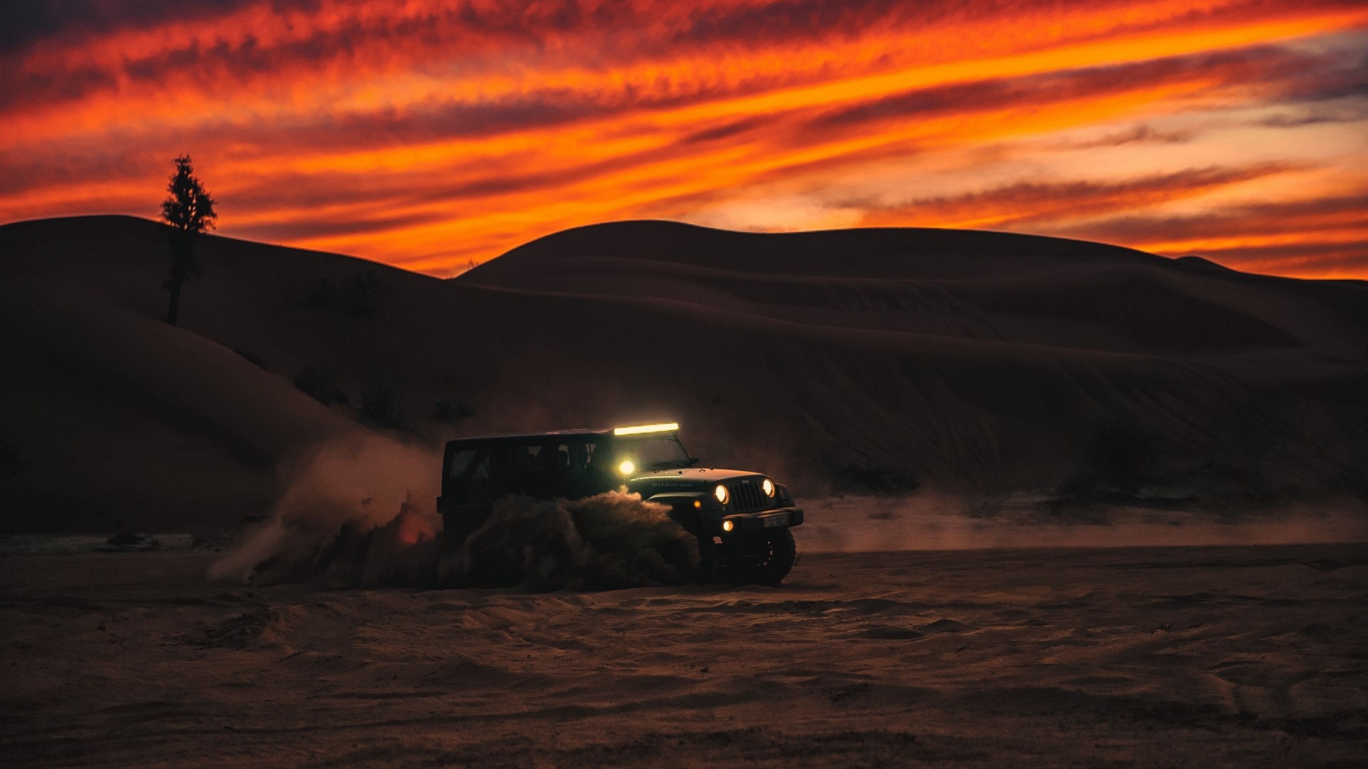 Jeep driving through sand dunes at sunset HD Wallpaper