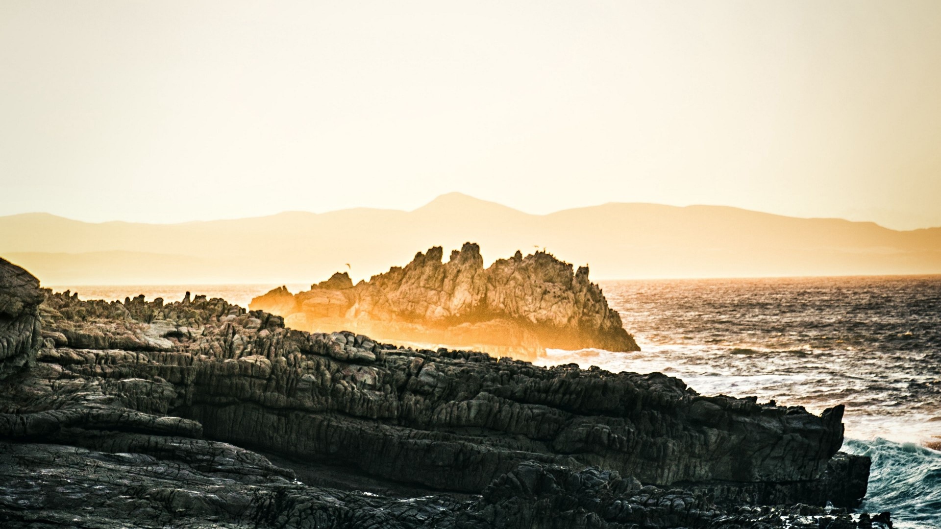 Rocky coastline with ocean waves at sunset HD Wallpaper