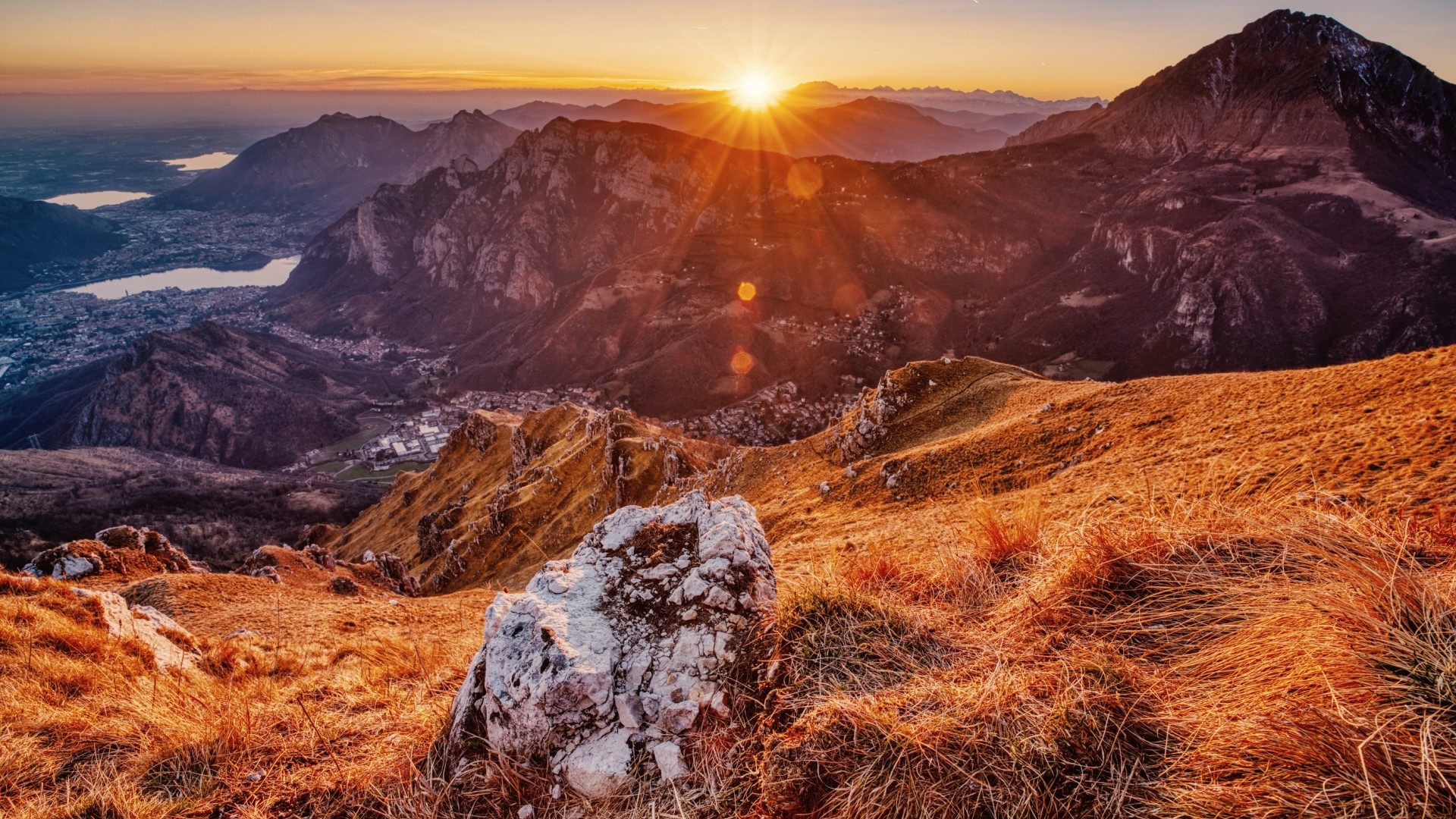 Mountain landscape at sunrise with sunburst over peaks HD Wallpaper