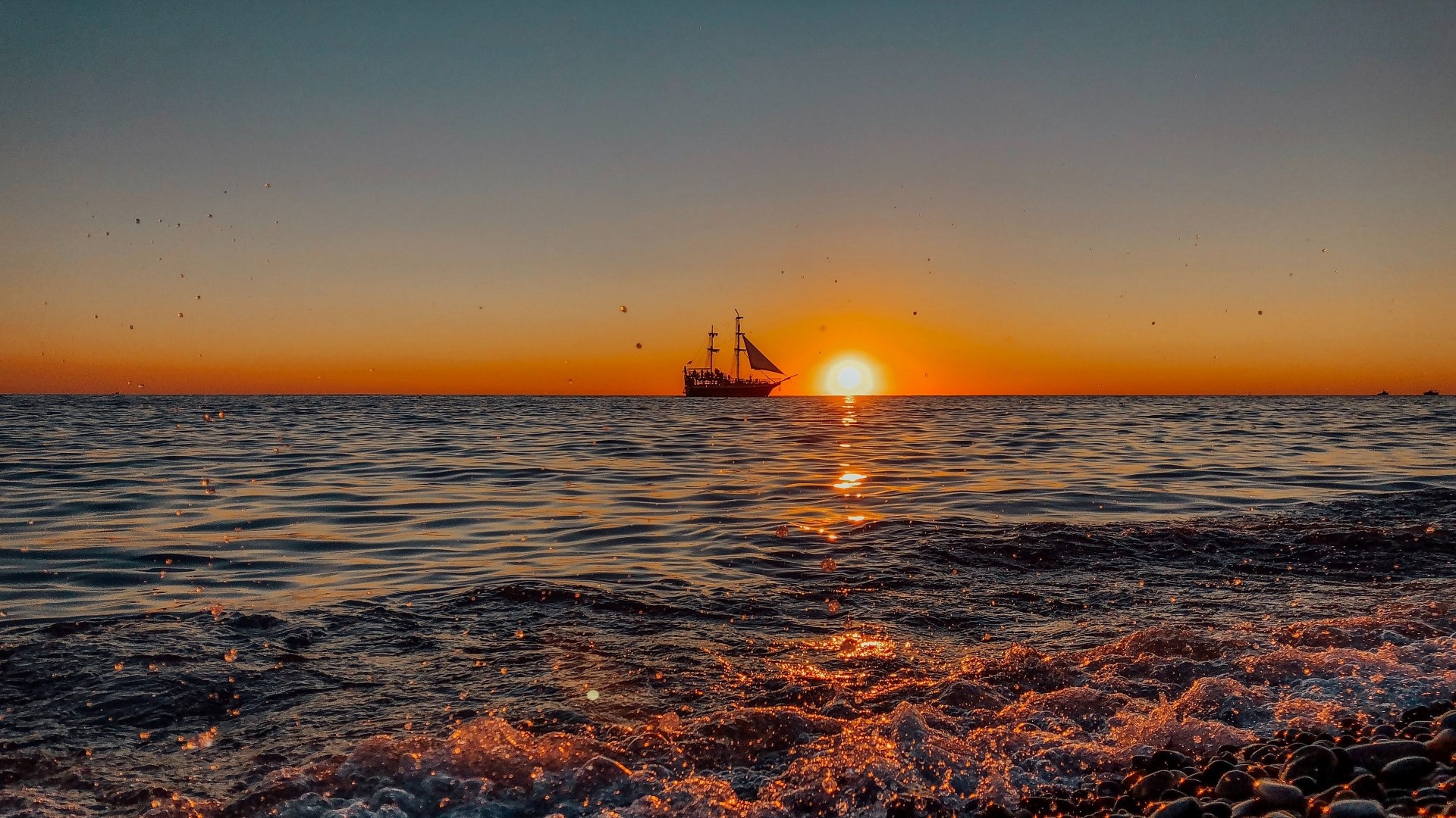 Ship sailing at sunset over the ocean HD Wallpaper