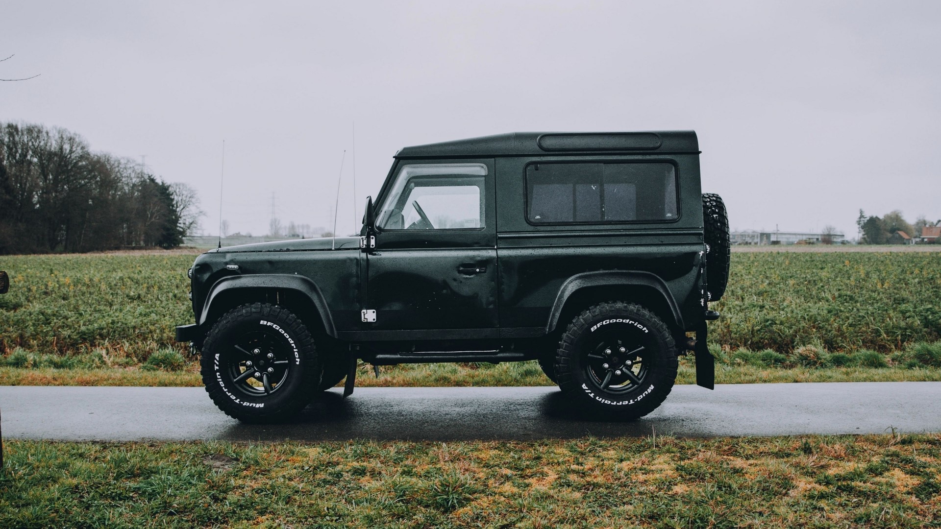 Dark green Land Rover Defender parked on a wet road HD Wallpaper
