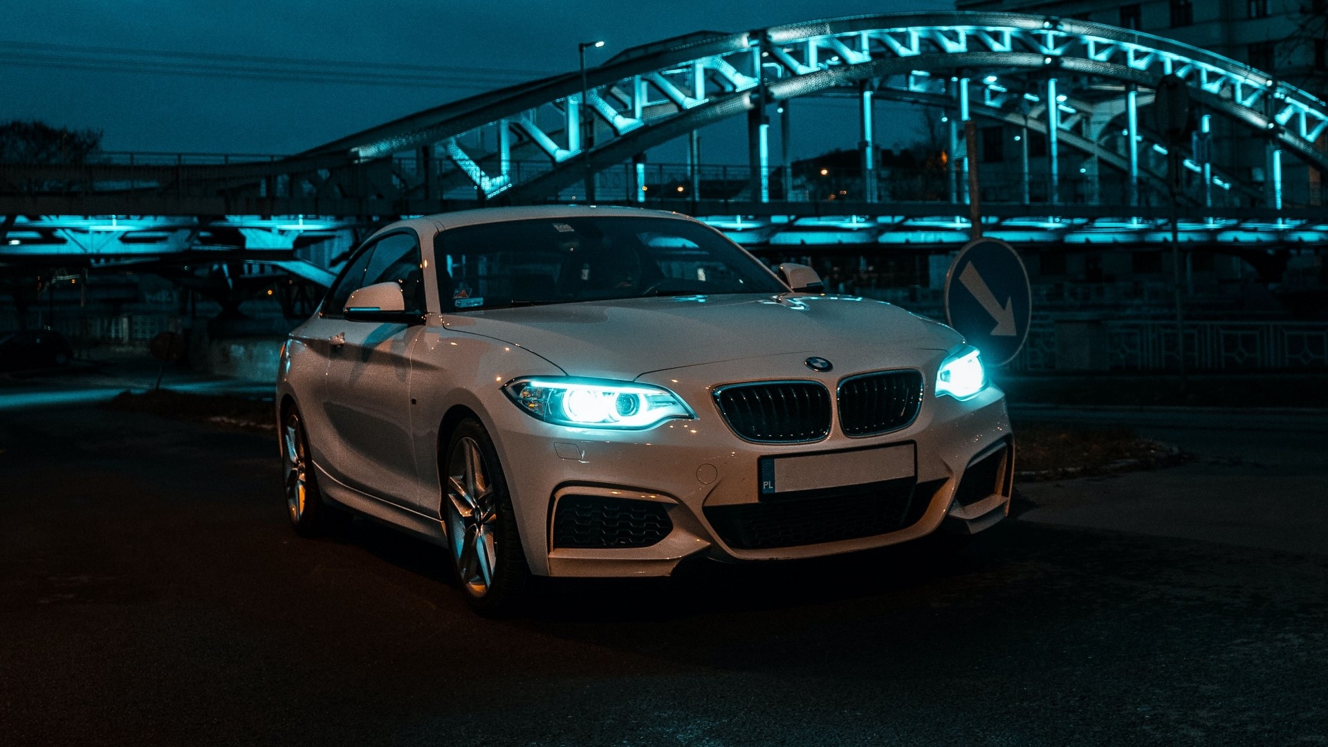 White BMW coupe parked under a blue illuminated bridge at night HD Wallpaper