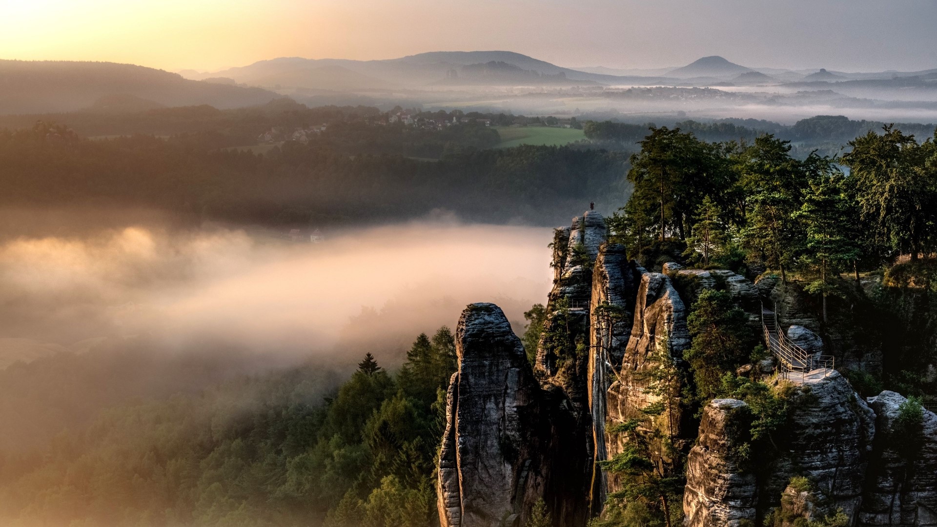 Misty mountains and rock formations at sunrise HD Wallpaper