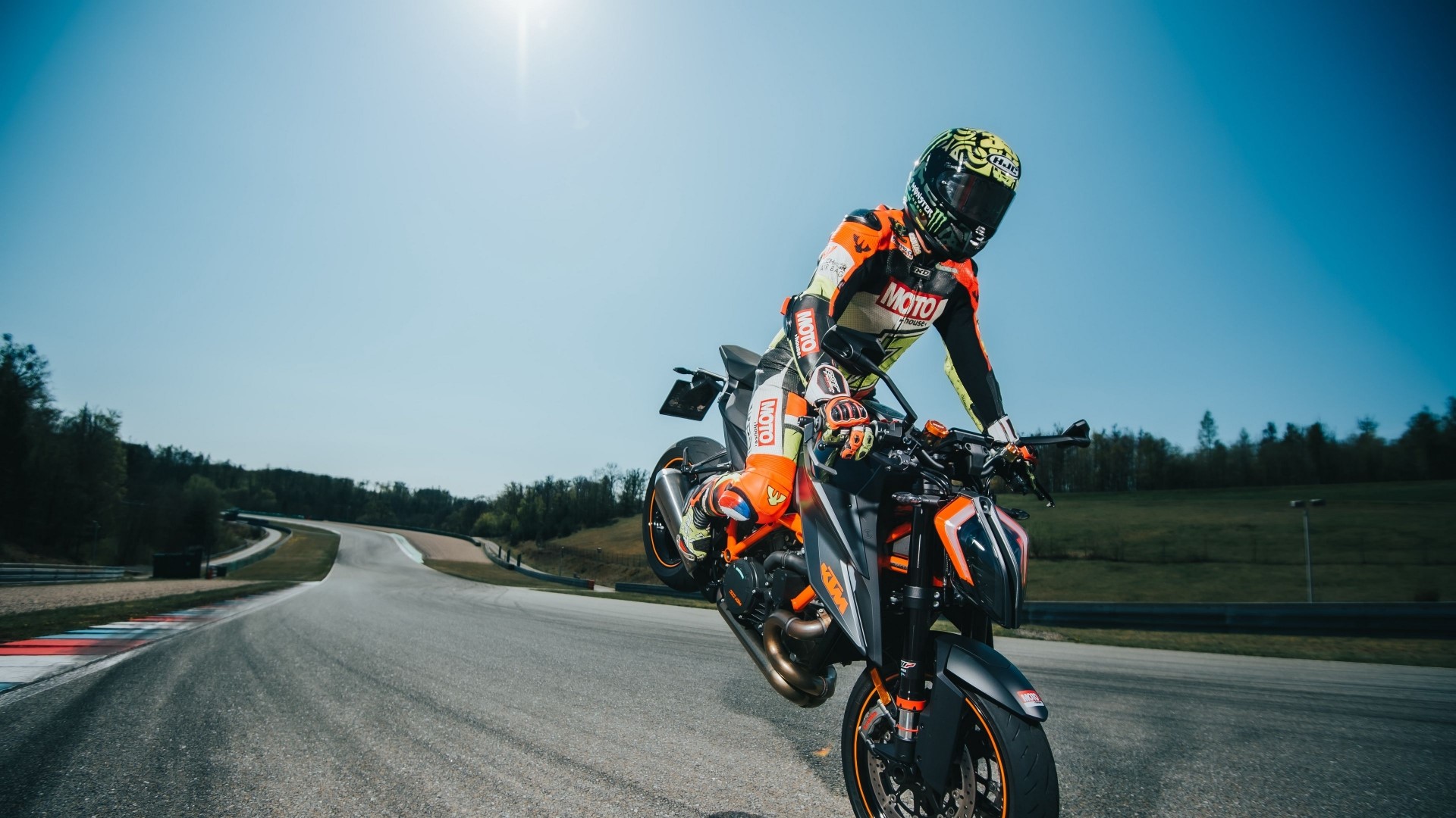 Motorcyclist performing a wheelie on a race track HD Wallpaper