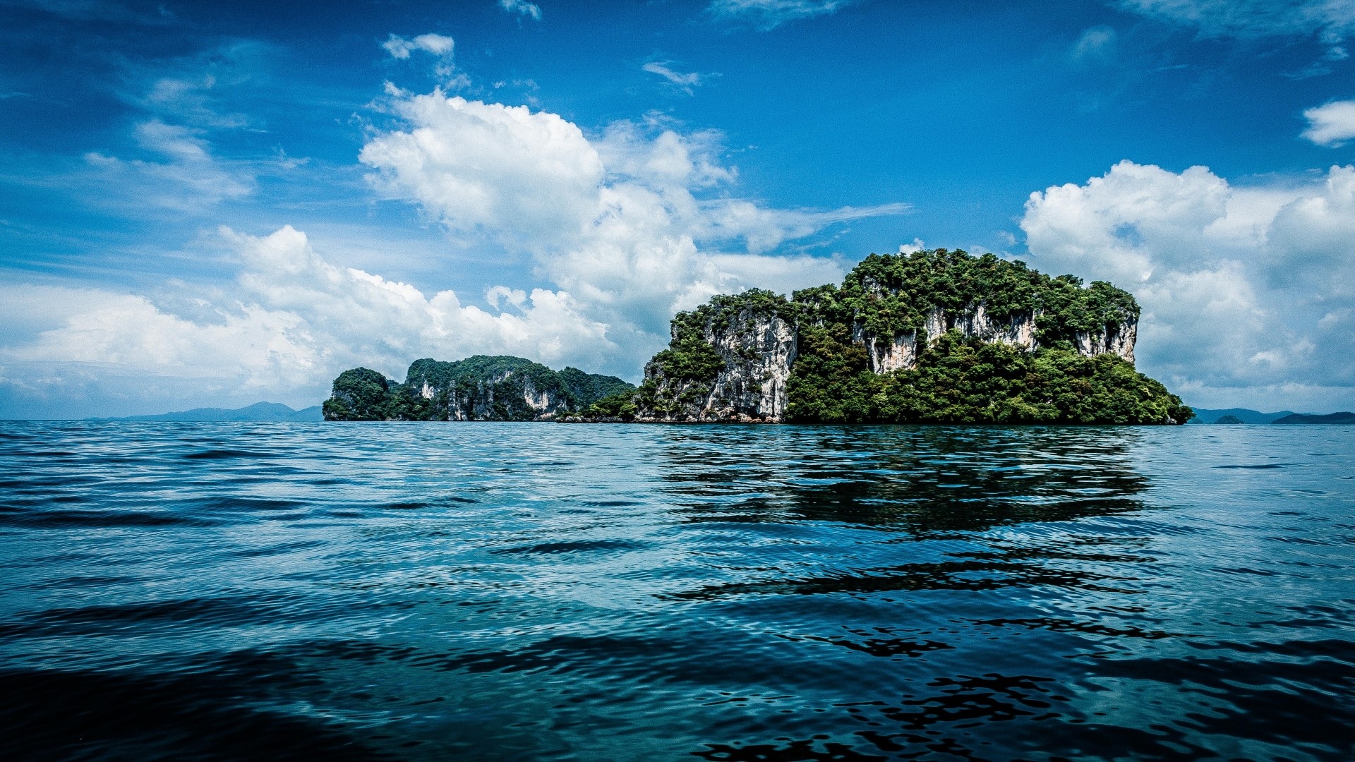 Islands in the ocean under a cloudy sky HD Wallpaper