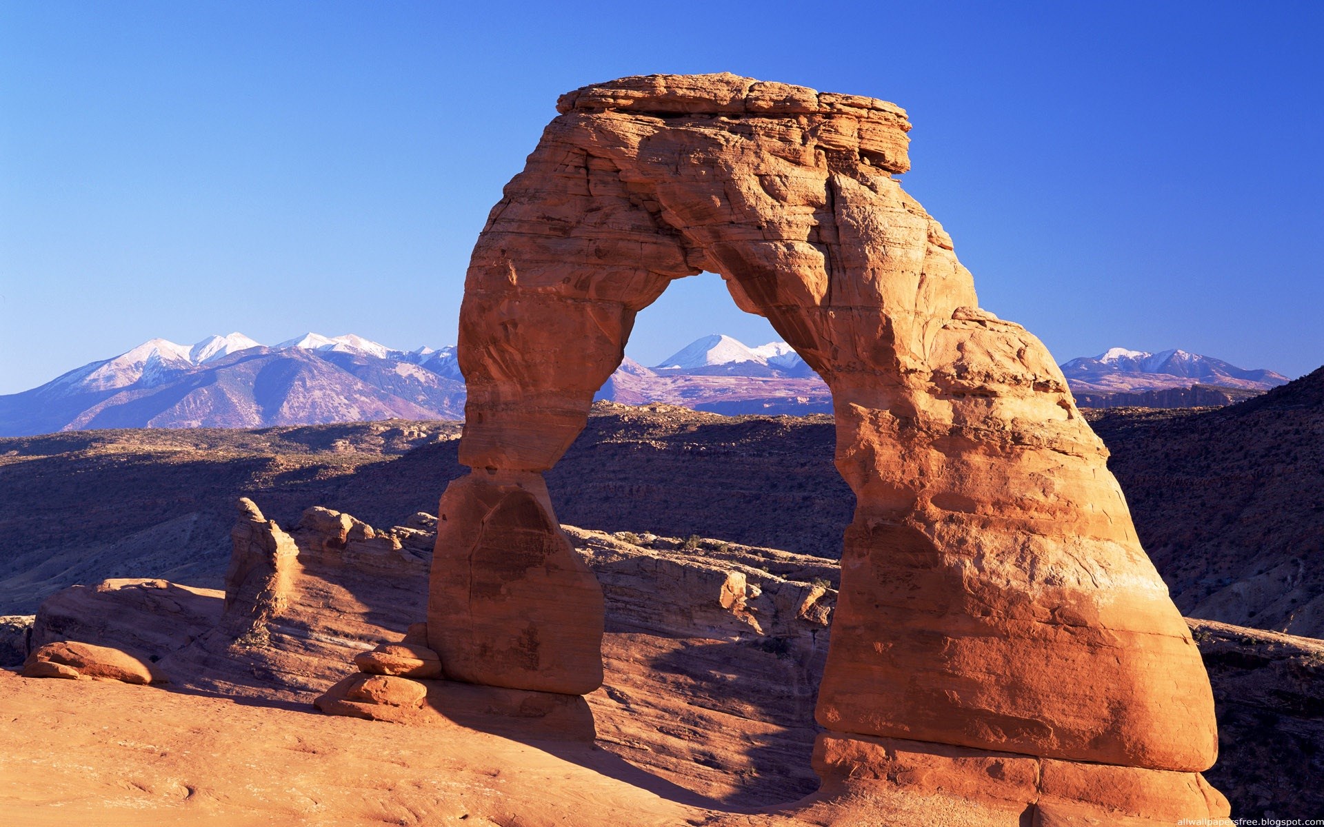 Delicate Arch with snow-capped mountains in the background HD Wallpaper