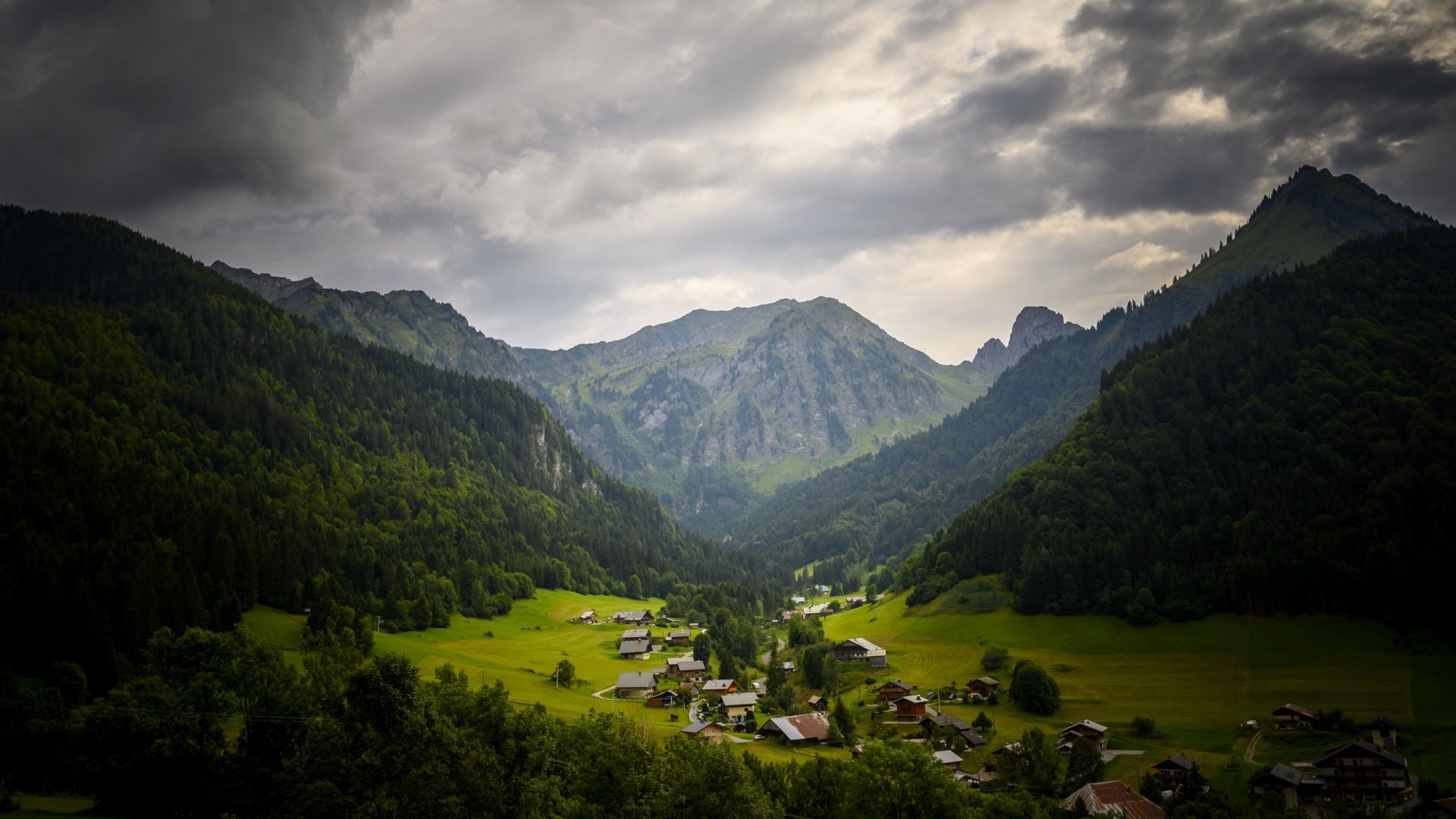 Village nestled in a green mountain valley HD Wallpaper