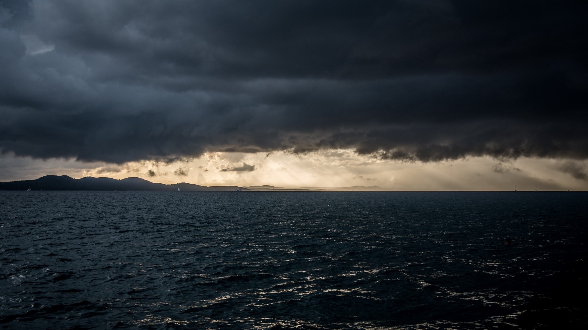 Dark storm clouds over the ocean horizon HD Wallpaper