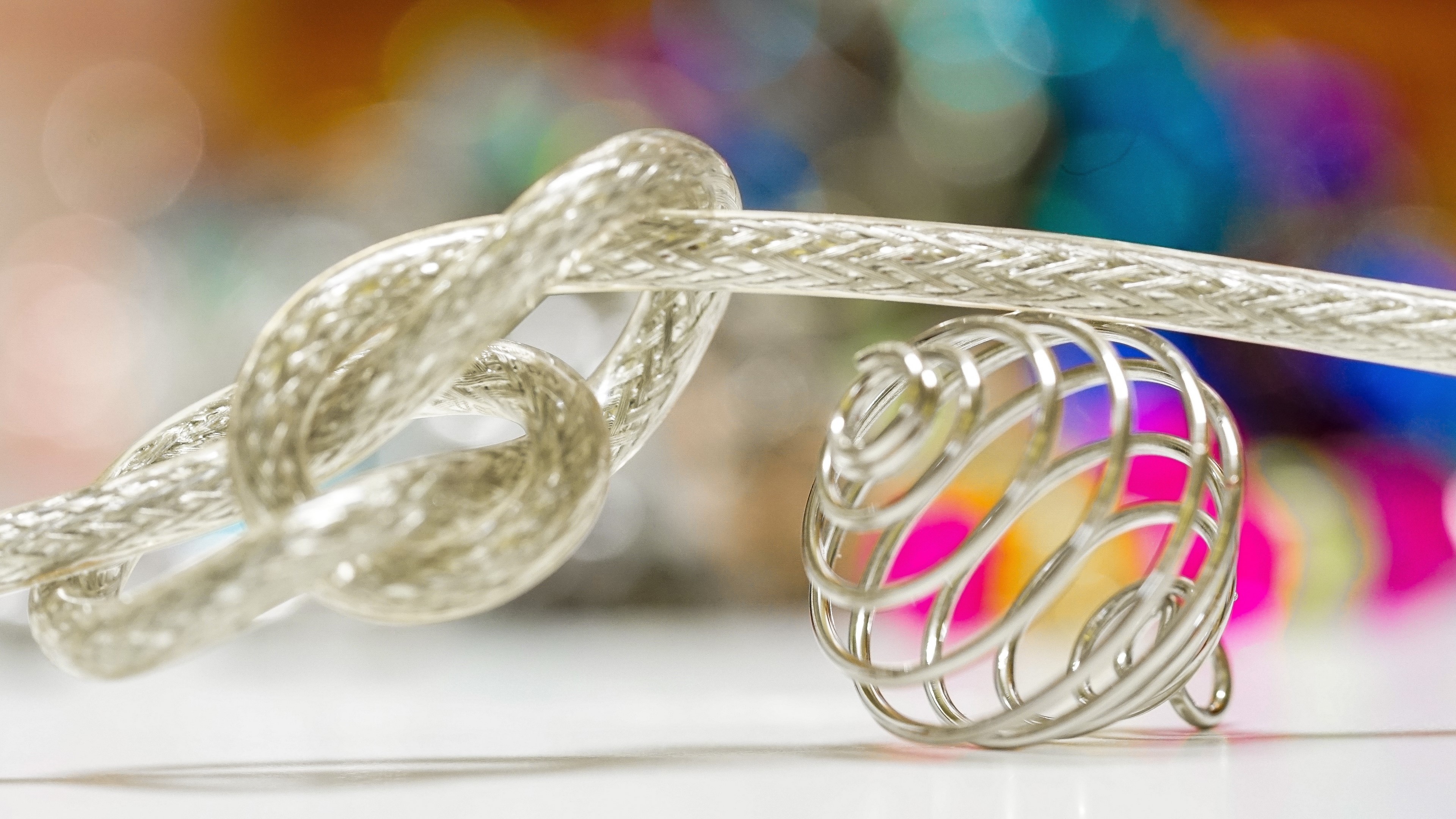 4K braided cable tied in a knot near a wire cage HD Wallpaper