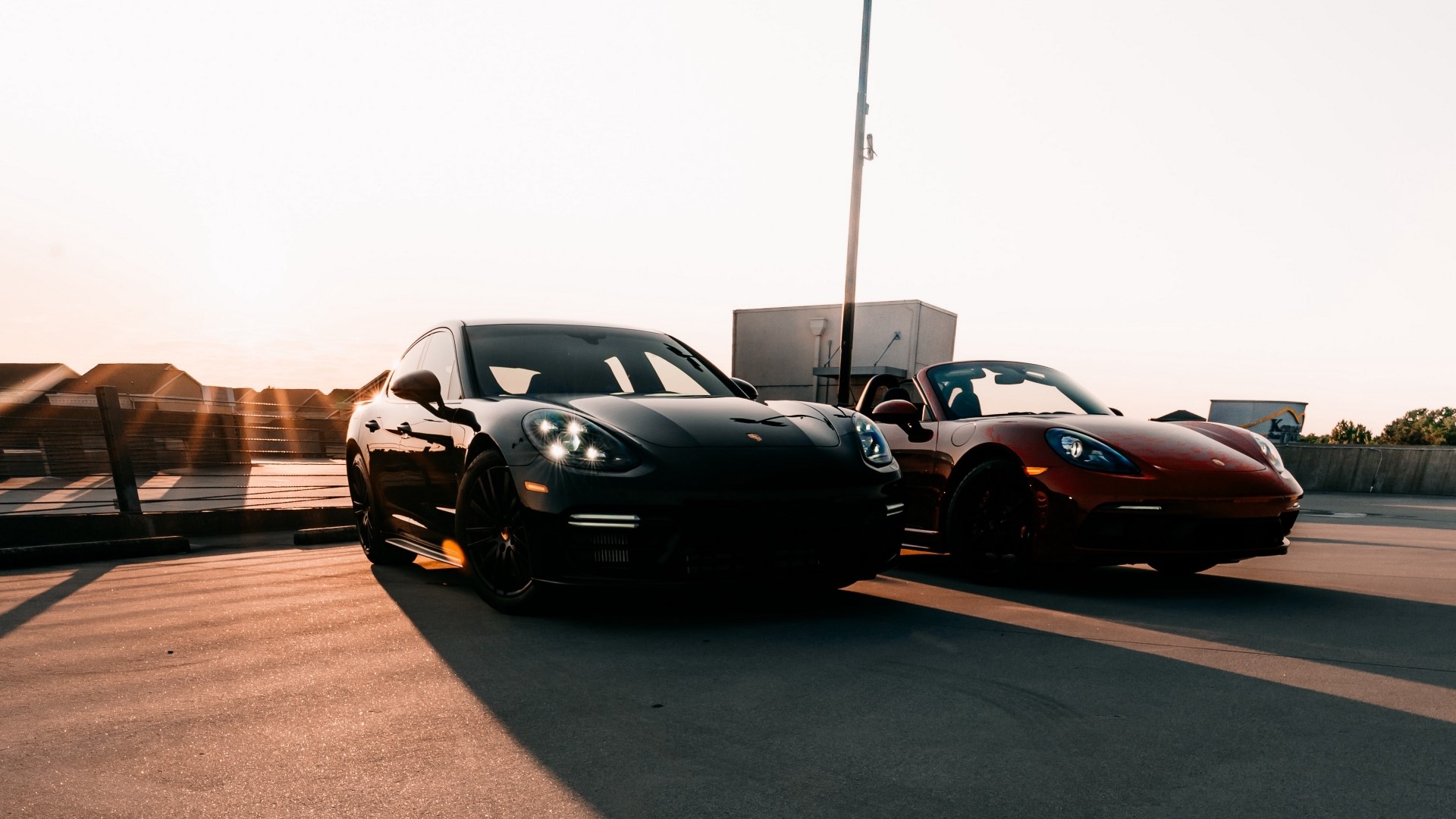 Two Porsche cars parked on a rooftop at sunset HD Wallpaper