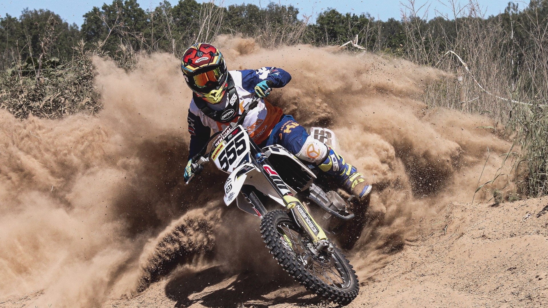Motocross rider with number 555 kicking up dust HD Wallpaper