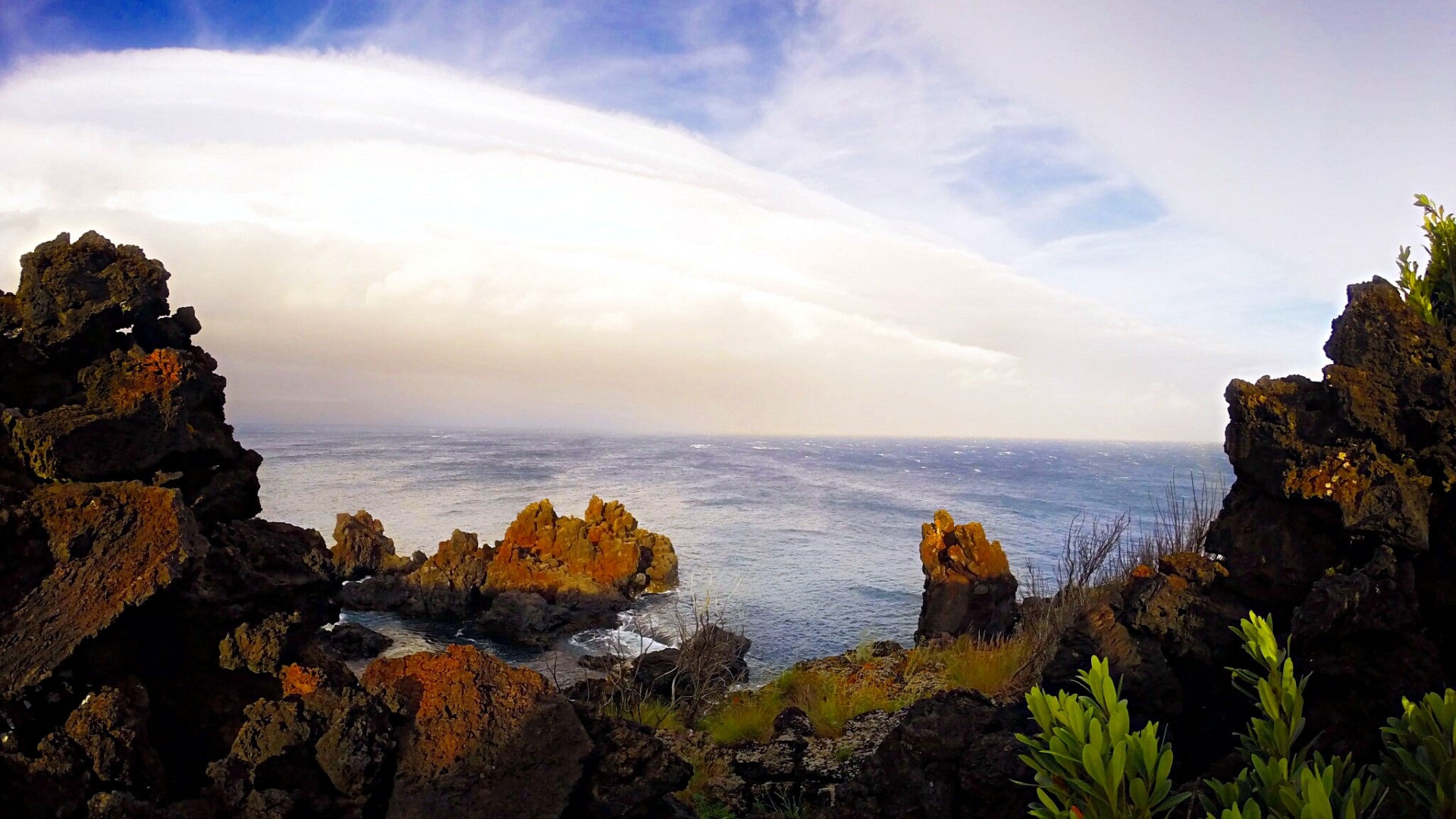 Rocky coastline overlooking the sea under a cloudy sky HD Wallpaper