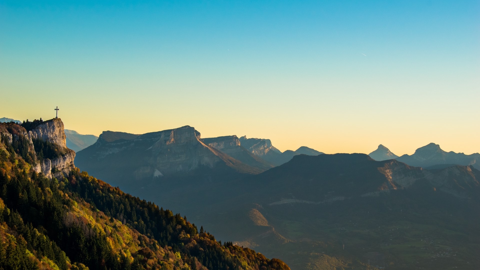 Cross on a mountain peak at sunset HD Wallpaper