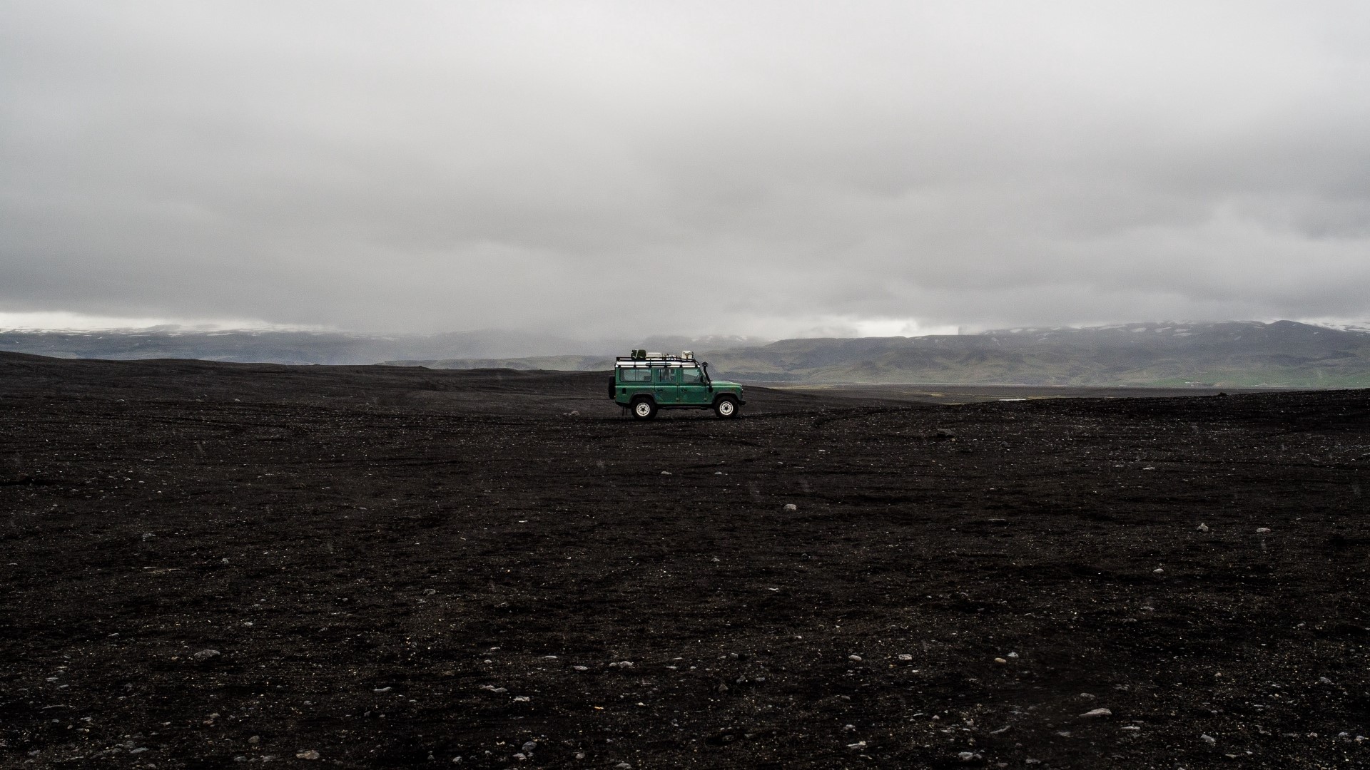 Green Land Rover Defender in a desolate landscape HD Wallpaper
