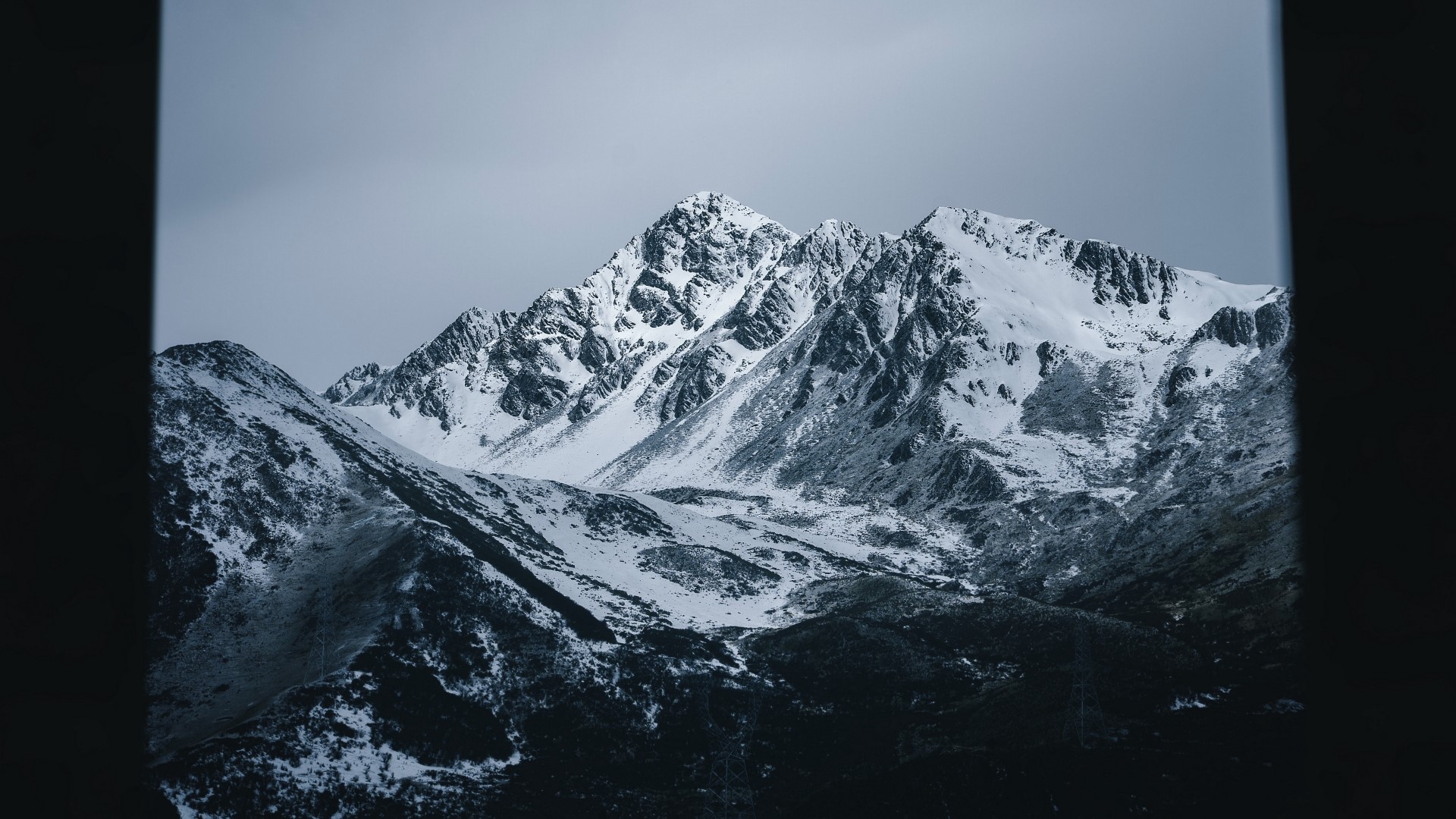 Snow-covered mountains under a cloudy sky HD Wallpaper