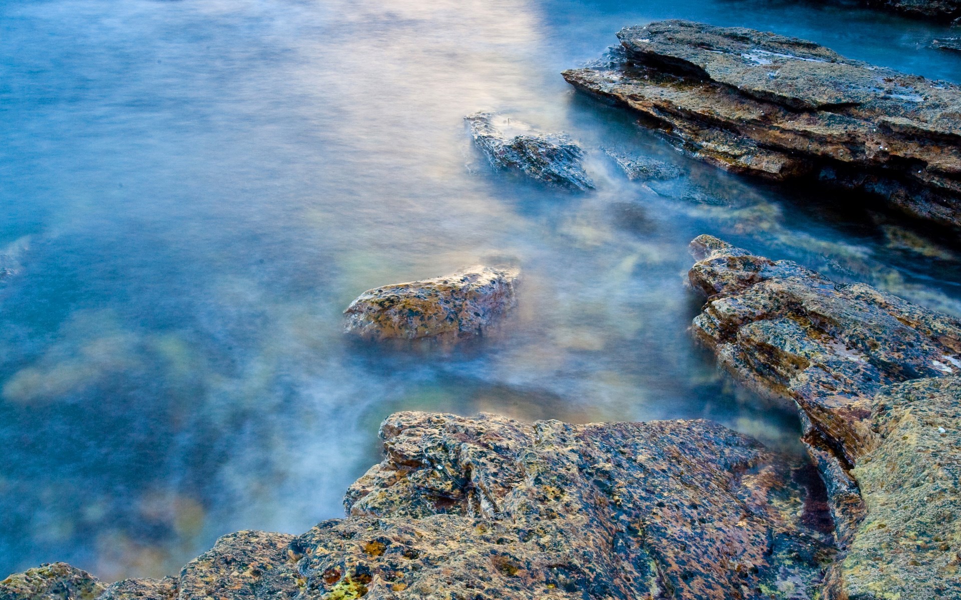 Rocky coastline with smooth water HD Wallpaper