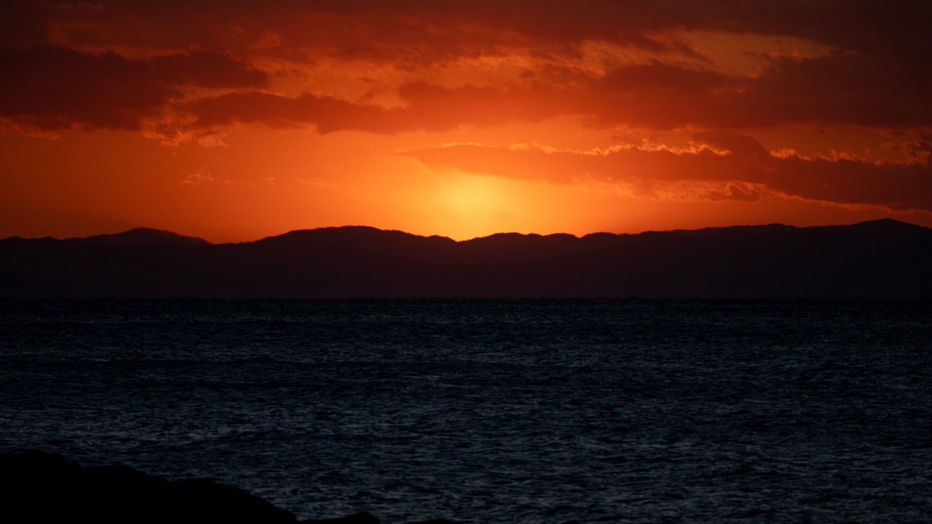 Sunset over the ocean with mountains HD Wallpaper