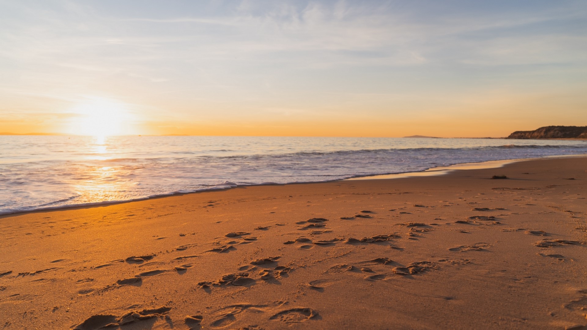 Beach at sunset with footprints HD Wallpaper