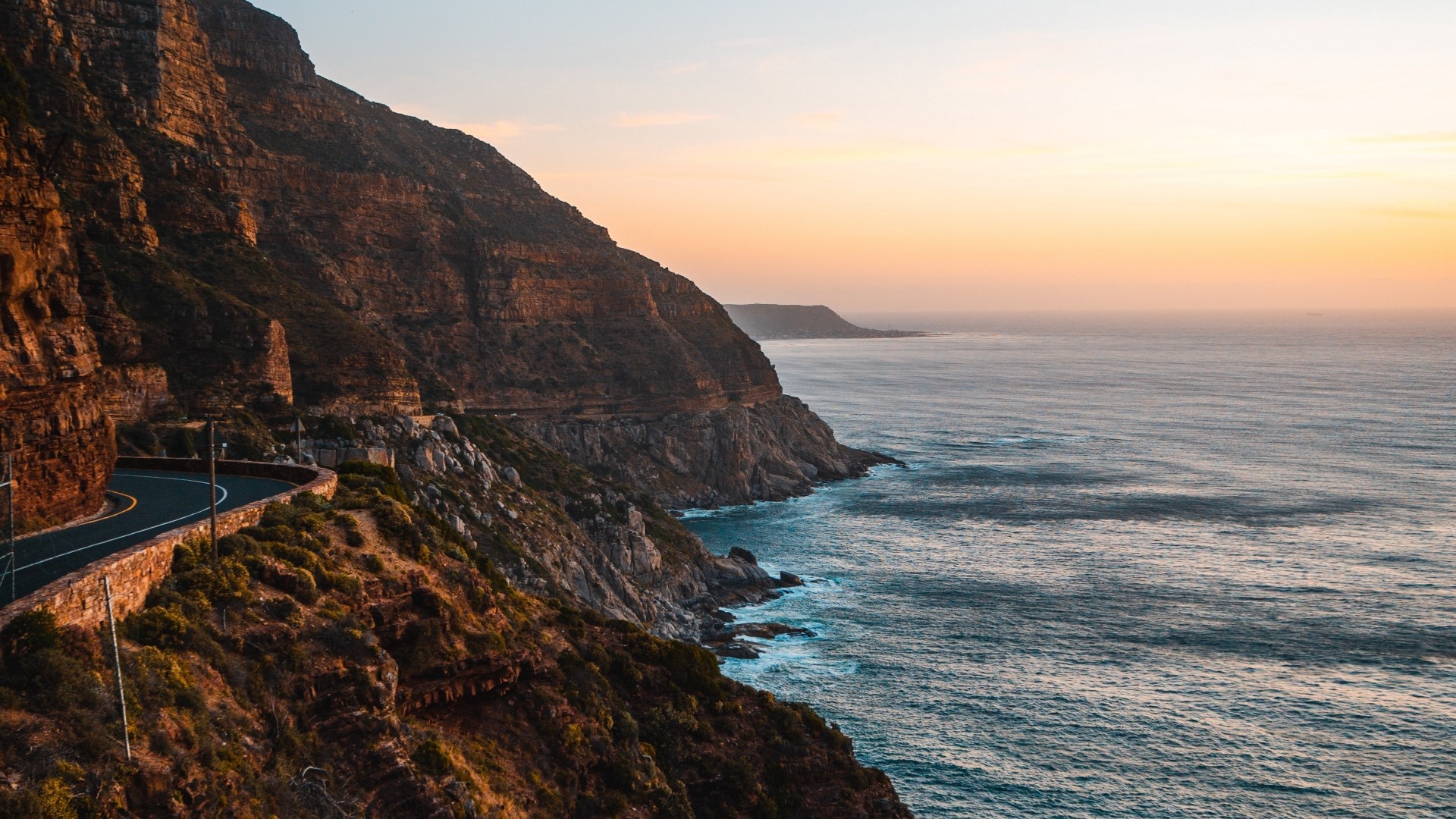Coastal road along a cliff by the ocean at sunset HD Wallpaper