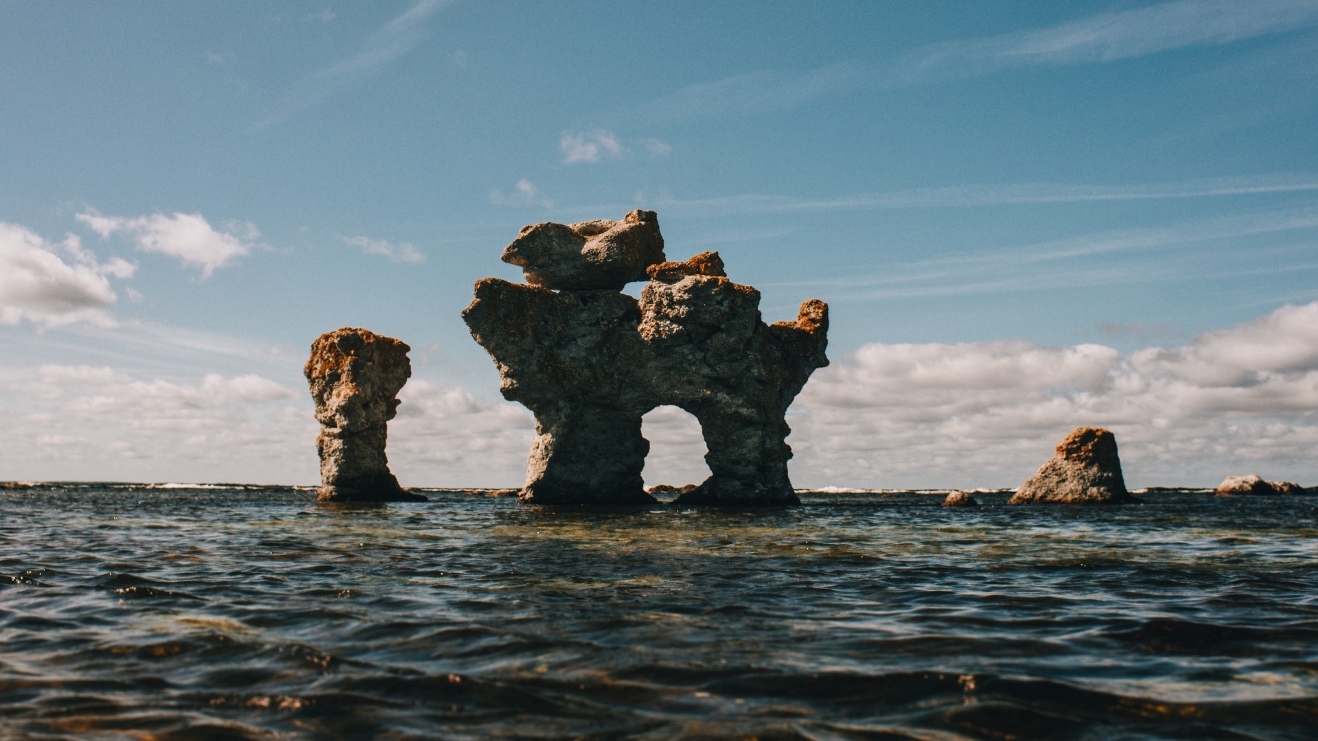 Sea stacks in the ocean under a cloudy sky HD Wallpaper