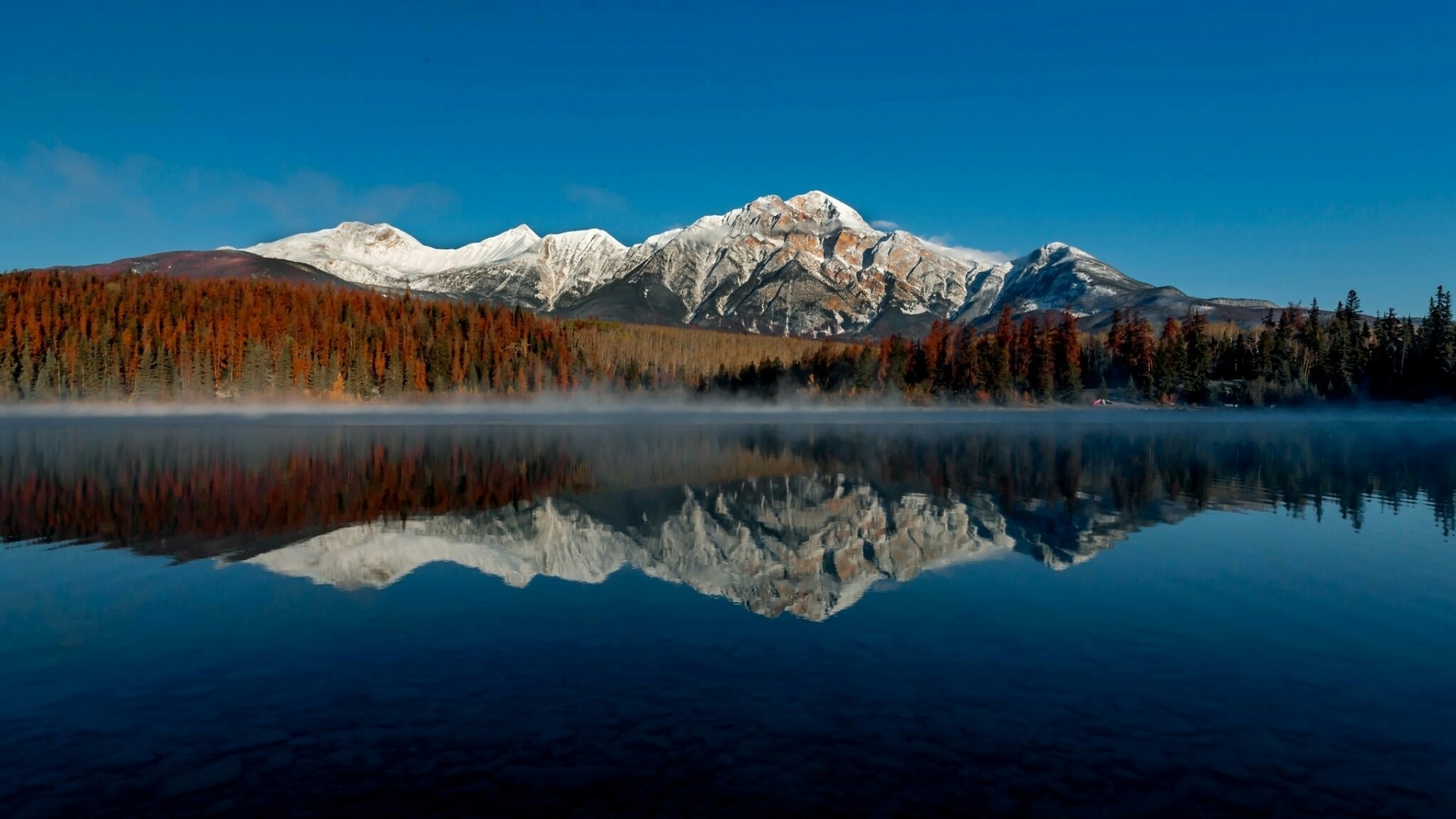 Mountain range reflected in a misty lake HD Wallpaper
