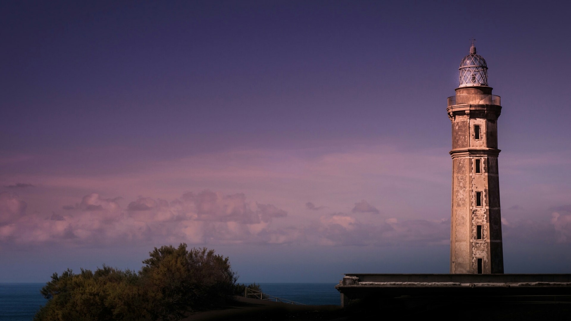 Lighthouse on a cliff overlooking the ocean at dusk HD Wallpaper