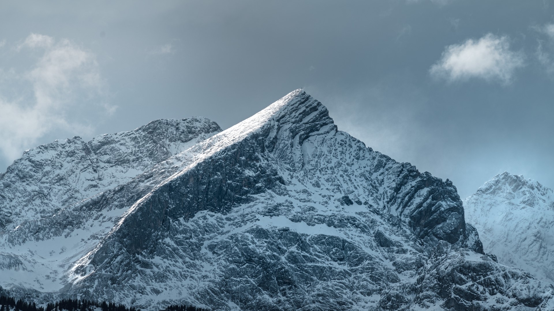 Snow-covered mountain peaks under a cloudy sky HD Wallpaper