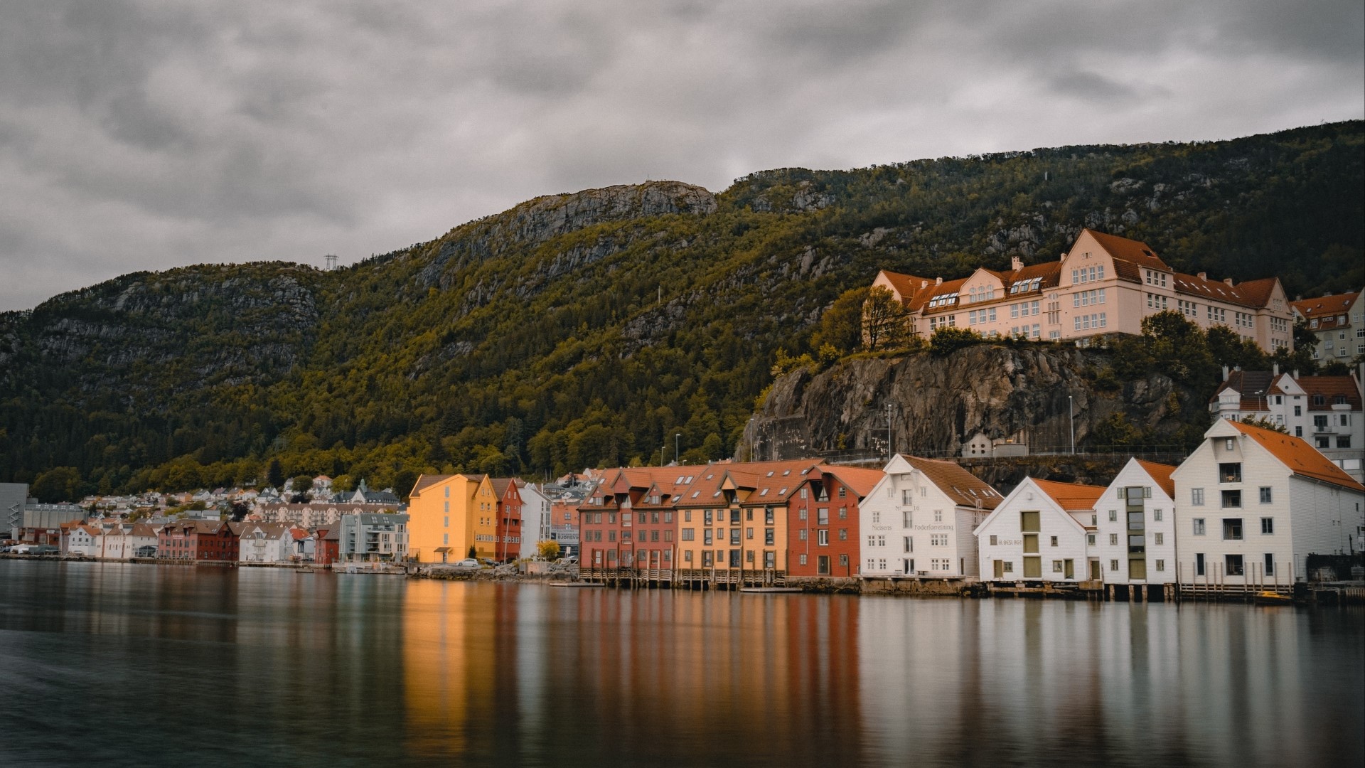 Colorful buildings on the waterfront with a forested mountain backdrop HD Wallpaper