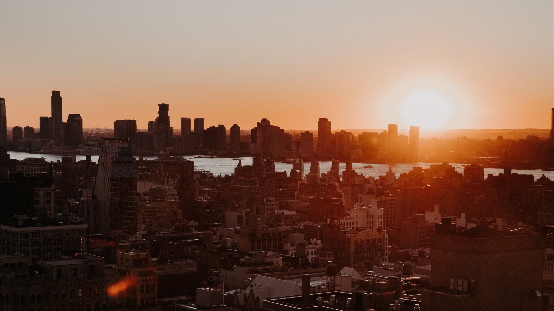 Sunset over a city skyline with a river HD Wallpaper