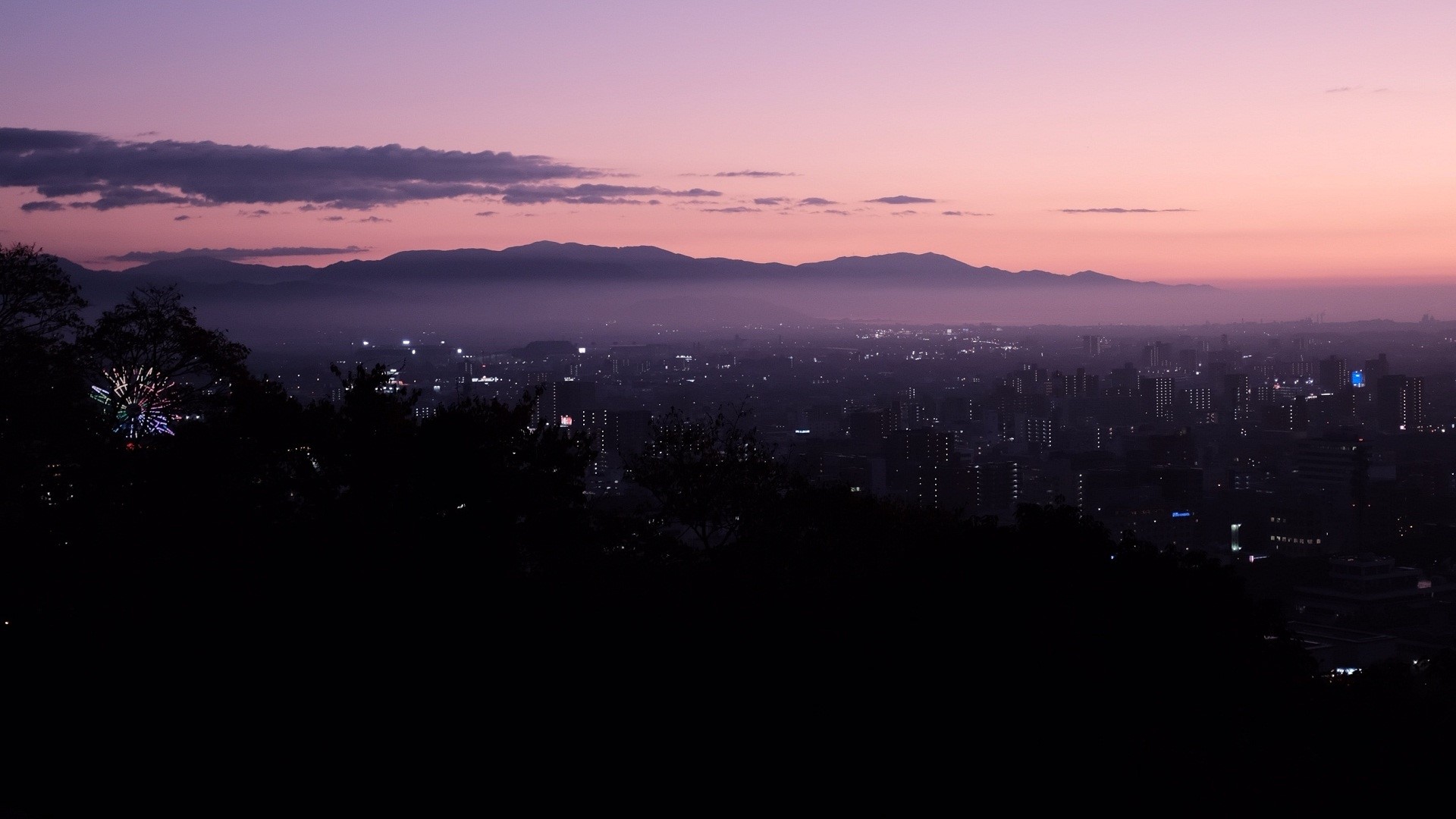 Cityscape at dusk with mountains and pinkish sky HD Wallpaper