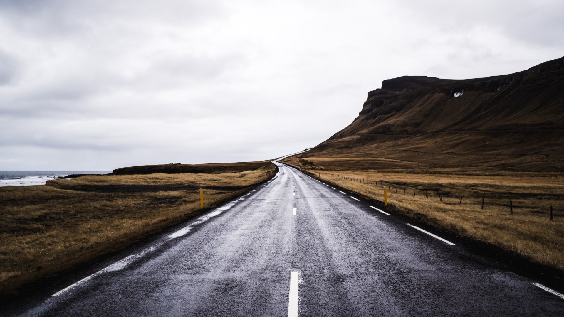 Wet asphalt road through a barren landscape HD Wallpaper
